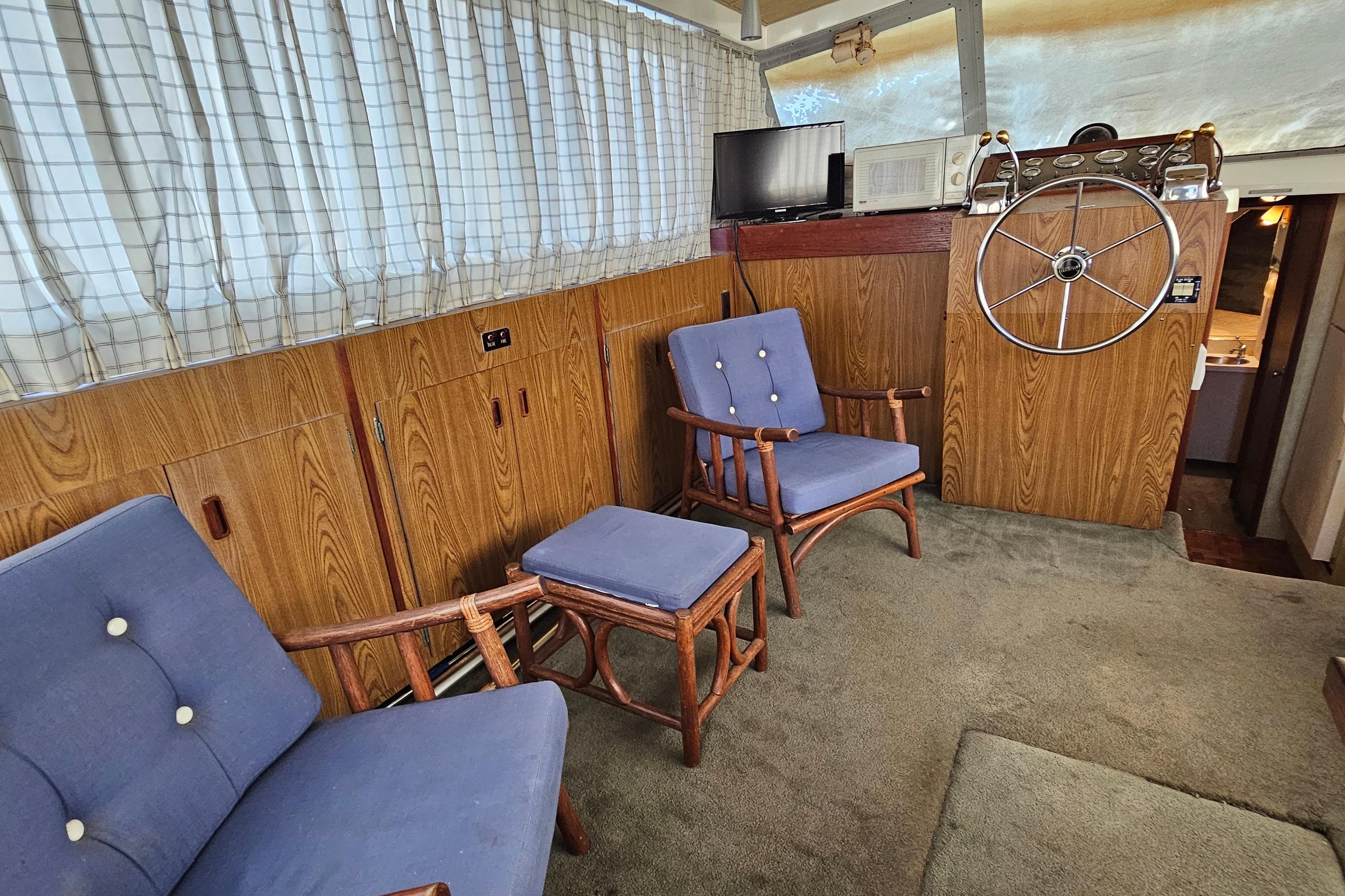 Interior of 1980 Bertram 42 Convertible with wooden paneling, blue chairs, and steering wheel.