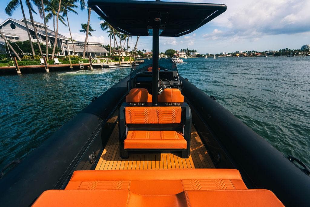 2024 Onda Magna boat with orange seats cruising on a scenic waterway.