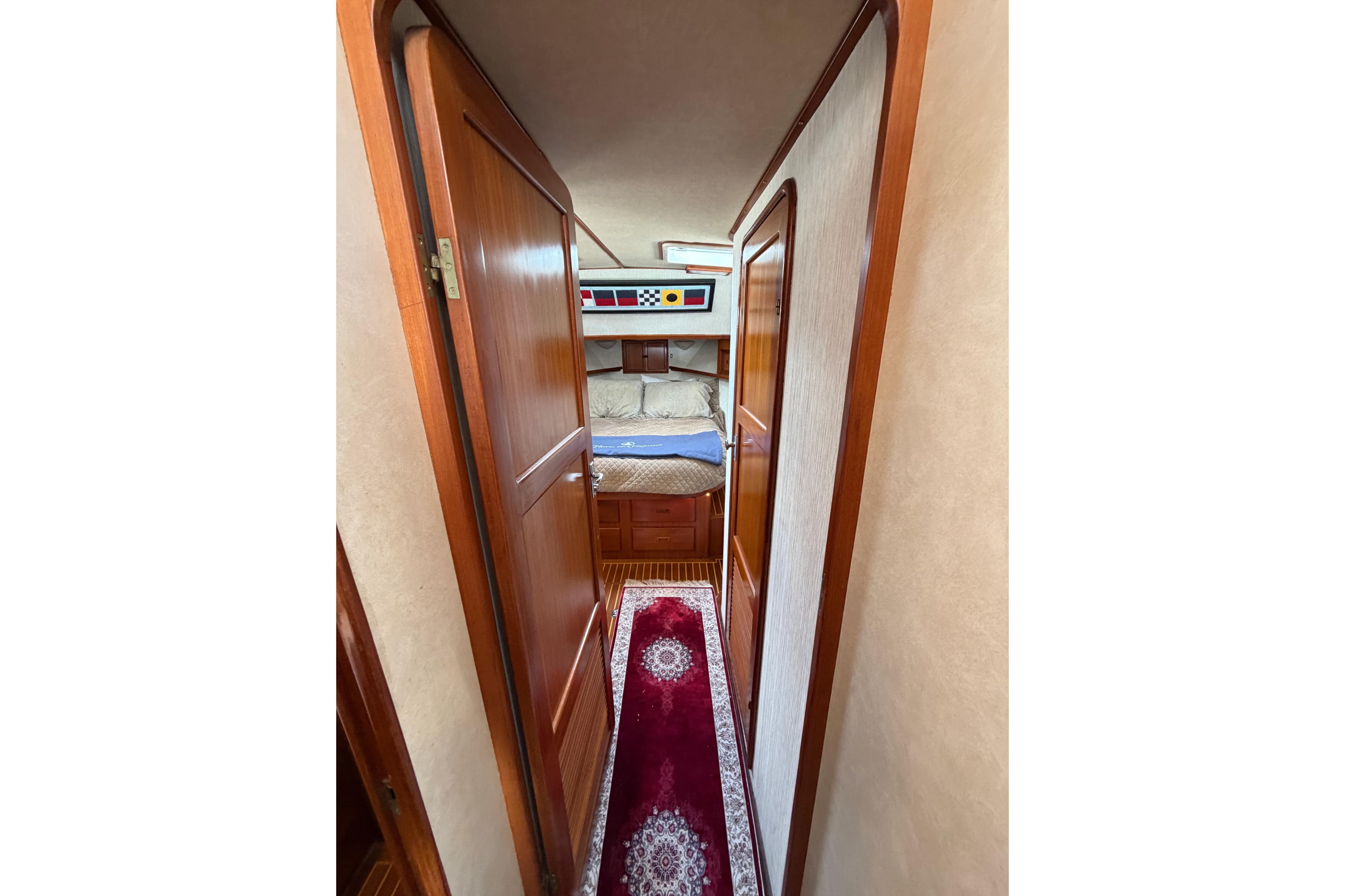 Interior hallway of 1988 Offshore Yachts 48 Sedan, featuring wood doors and cozy bedroom.