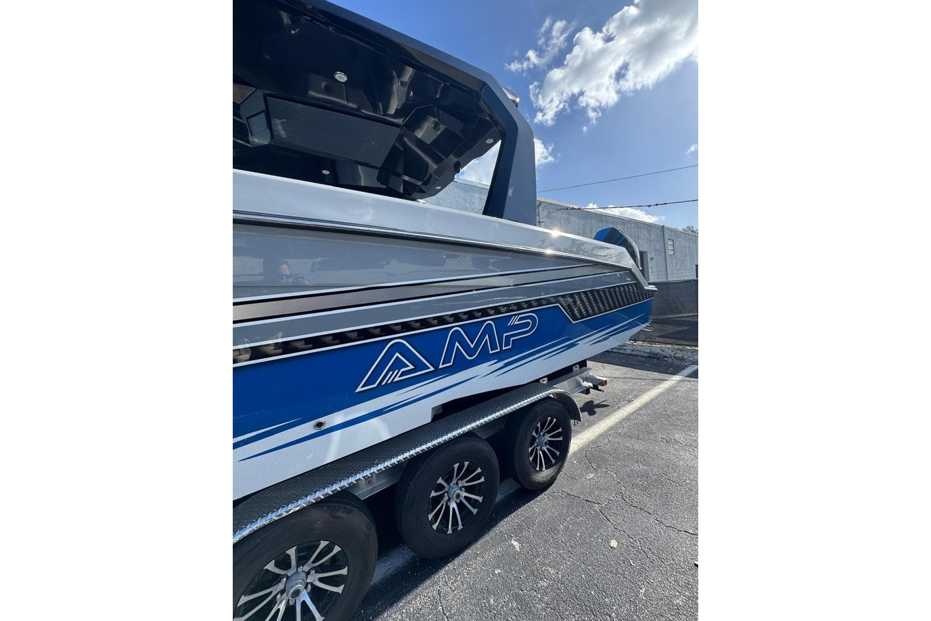 2023 AMP 333 boat on trailer, blue and white design, parked outdoors.