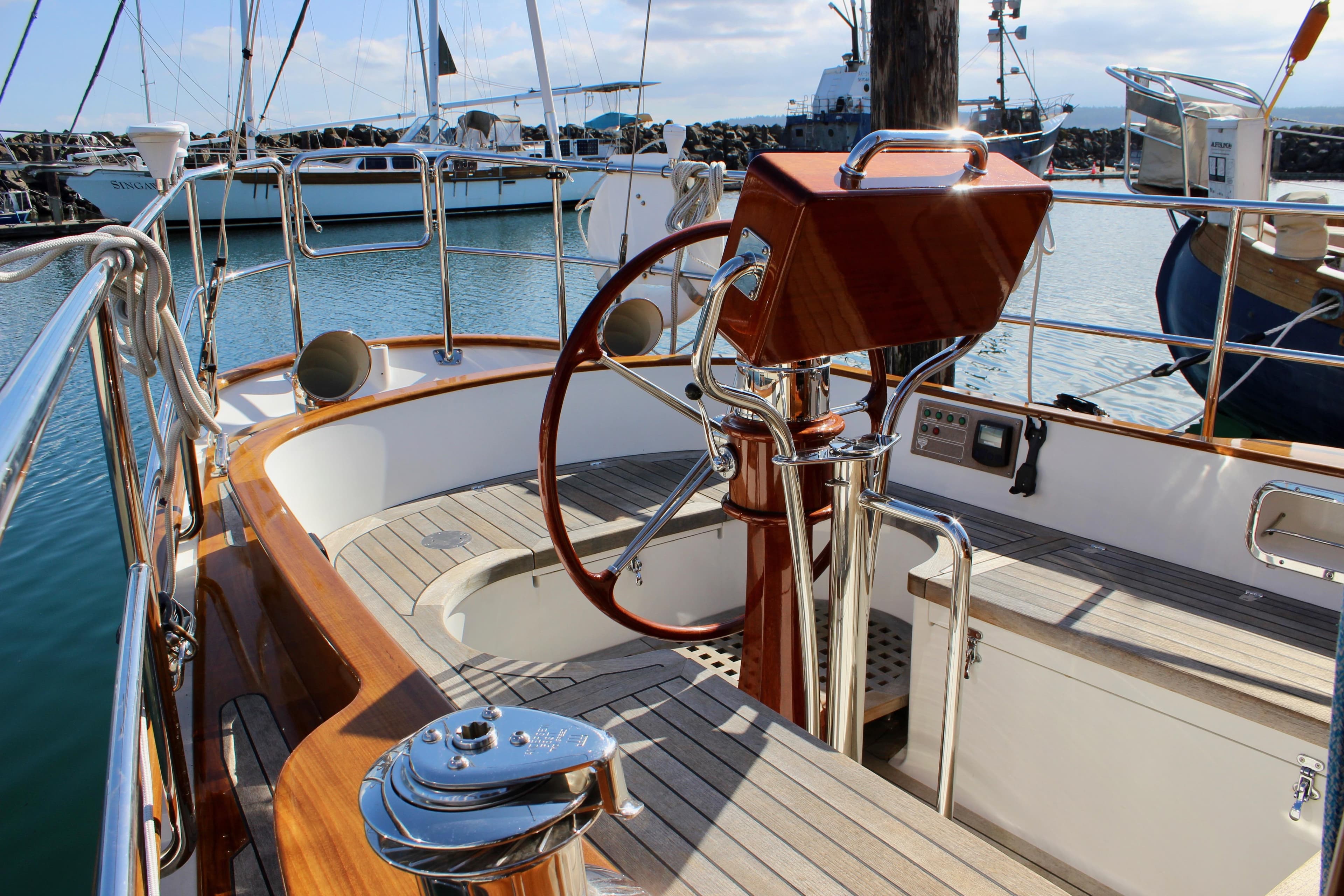 Cockpit of 2018 Cape George 45 sailboat with wooden accents and steering wheel in marina.