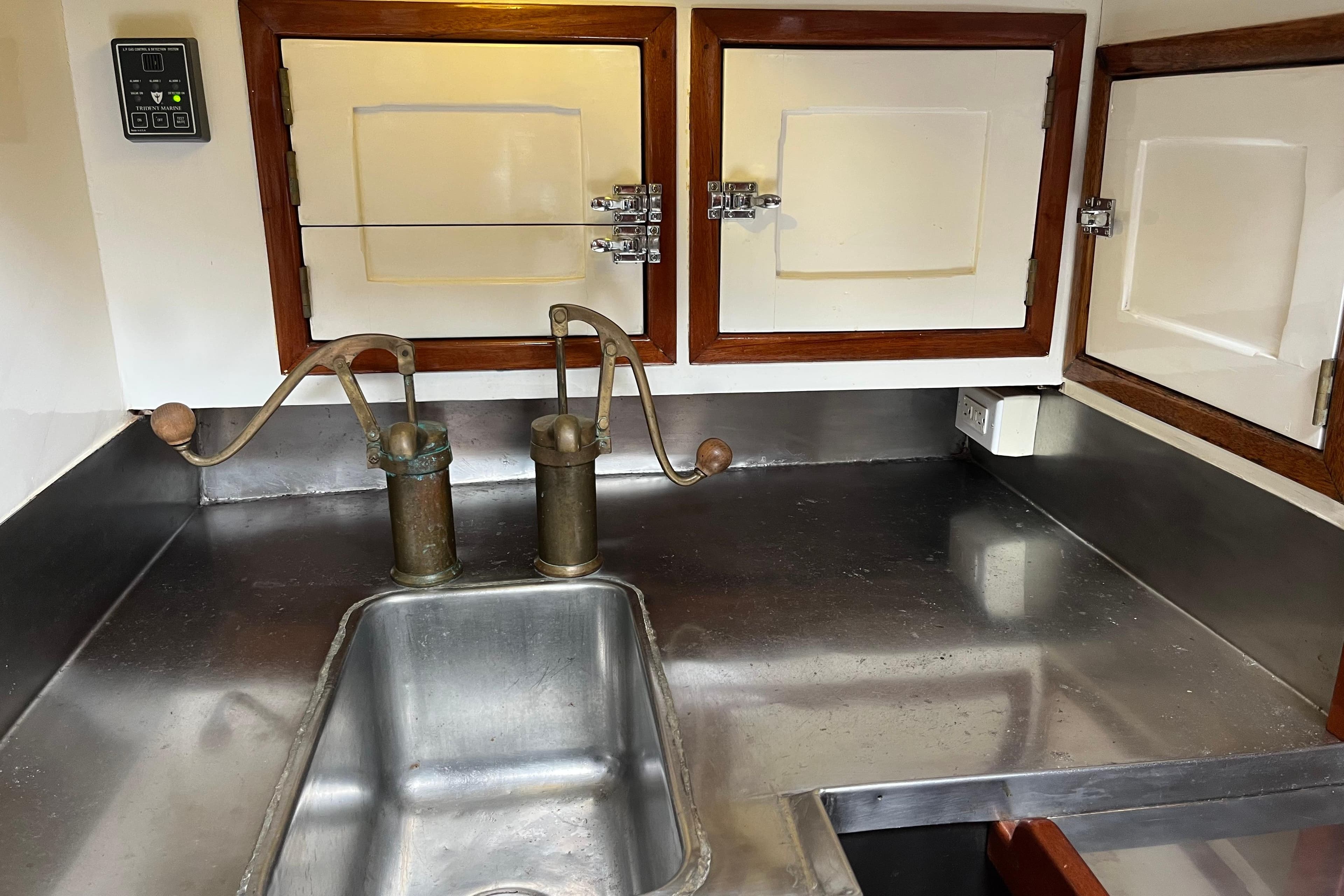 Vintage 1947 Murray Peterson Schooner galley with stainless steel sink and wooden cabinets.