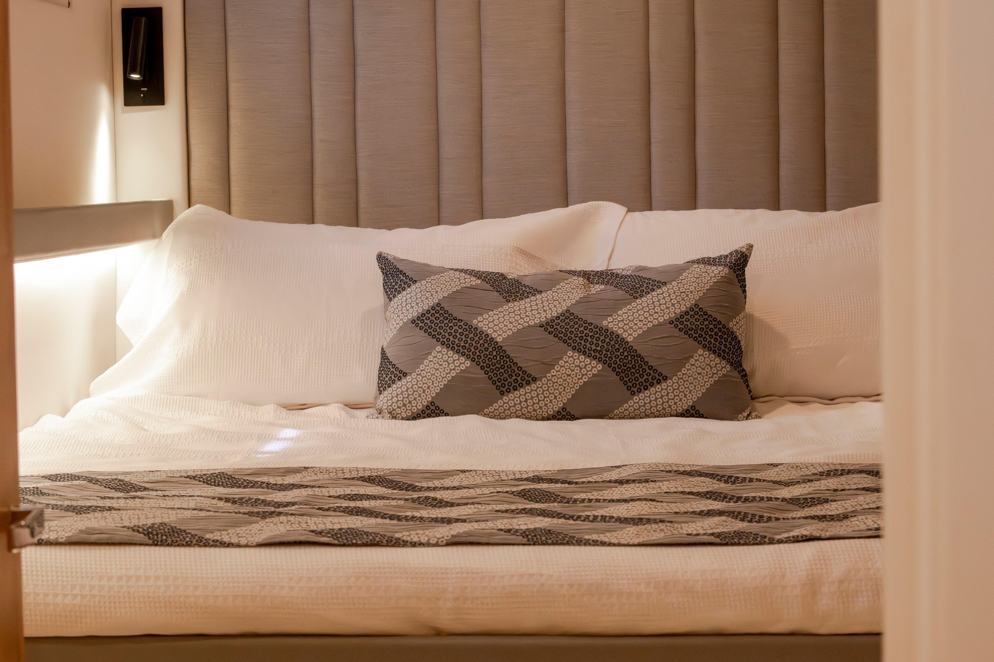 Luxurious bedroom interior in 2024 Bloomfield Custom 70 yacht, featuring elegant bedding and ambient lighting.