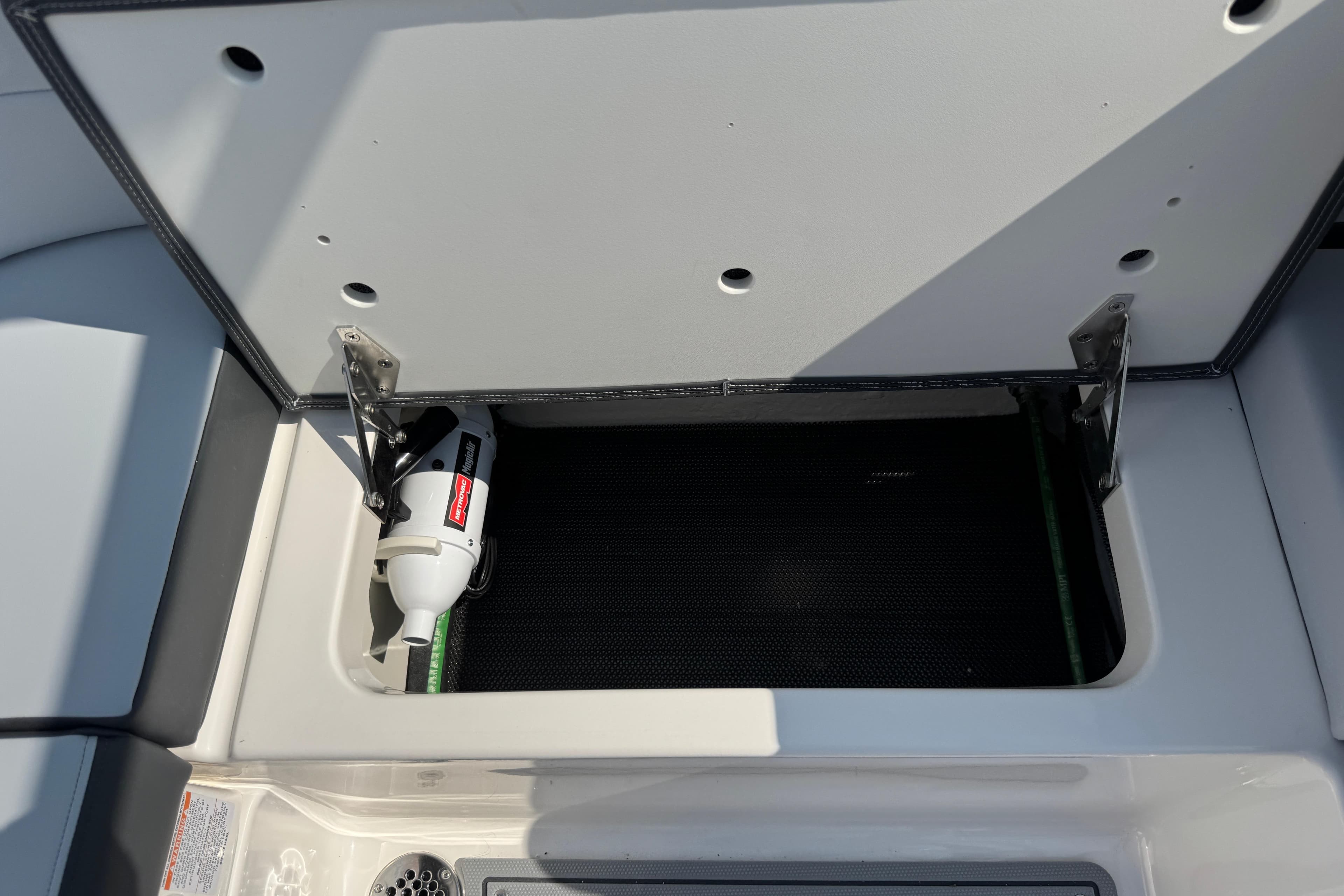 Open storage compartment in 2025 Chaparral 247 SSX boat, featuring a fire extinguisher.