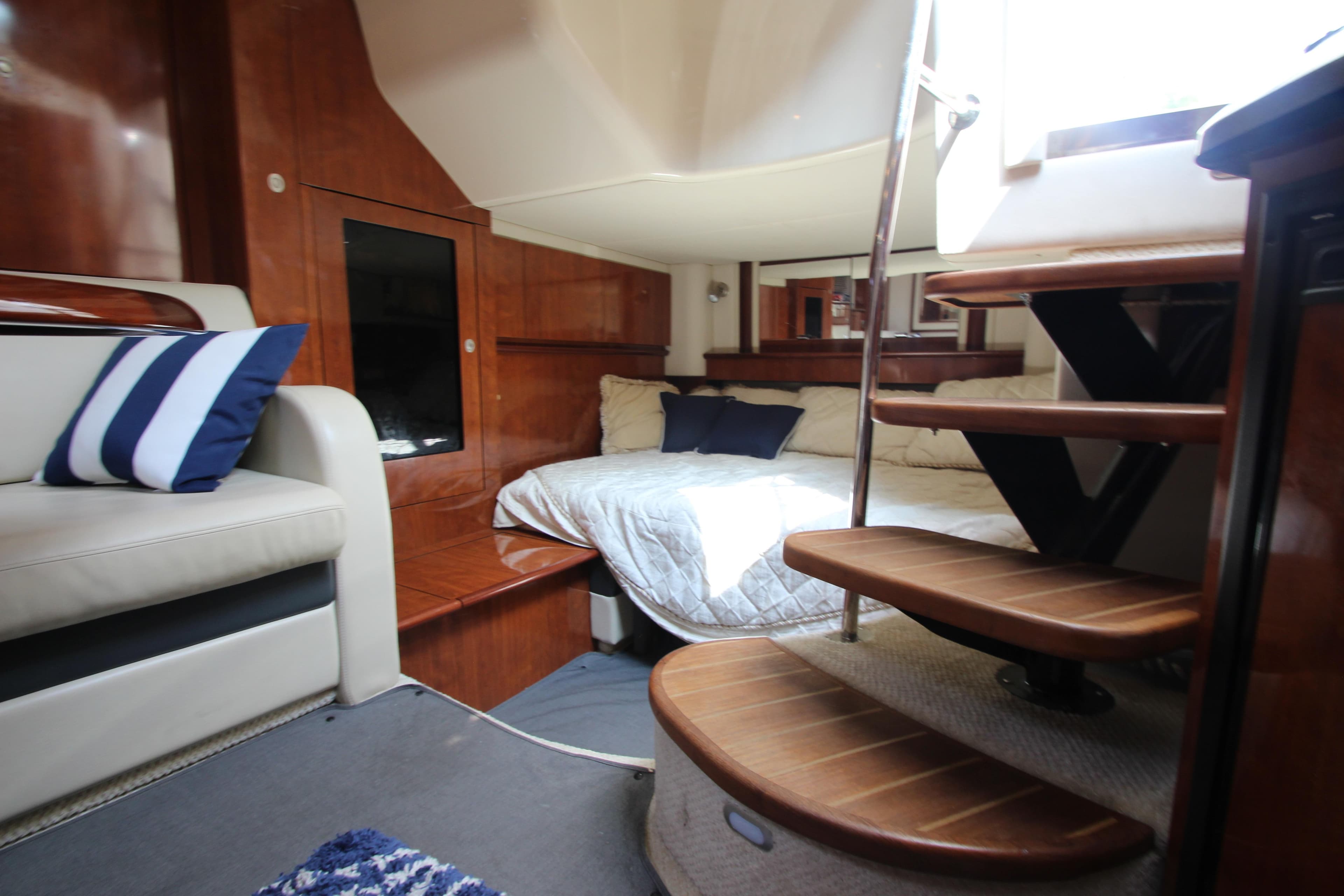 Interior of 2004 Sea Ray 40 Sundancer yacht with cozy bed and wooden stairs.