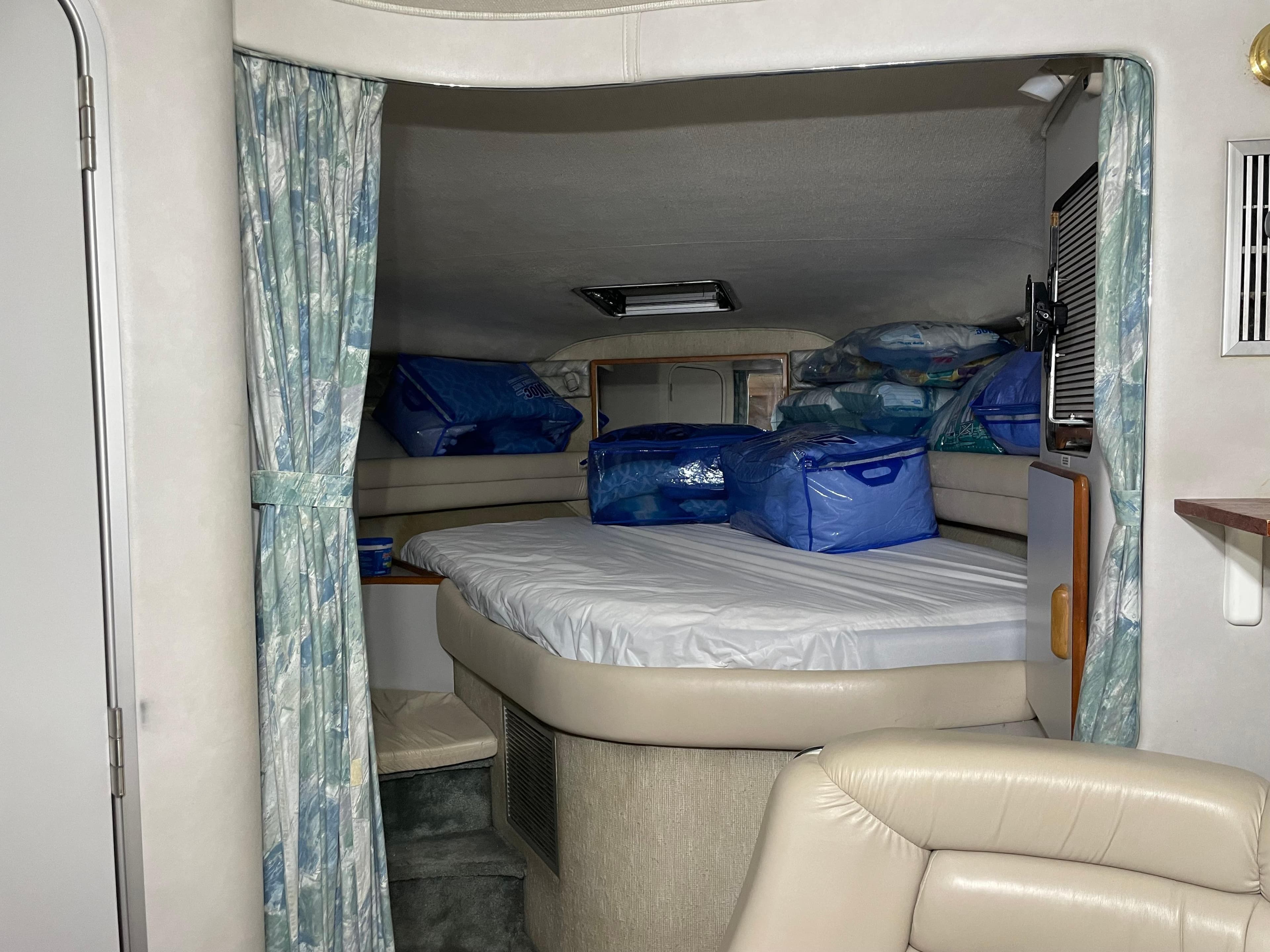 1991 Sea Ray 350 Sundancer cabin interior with bed and storage bags.