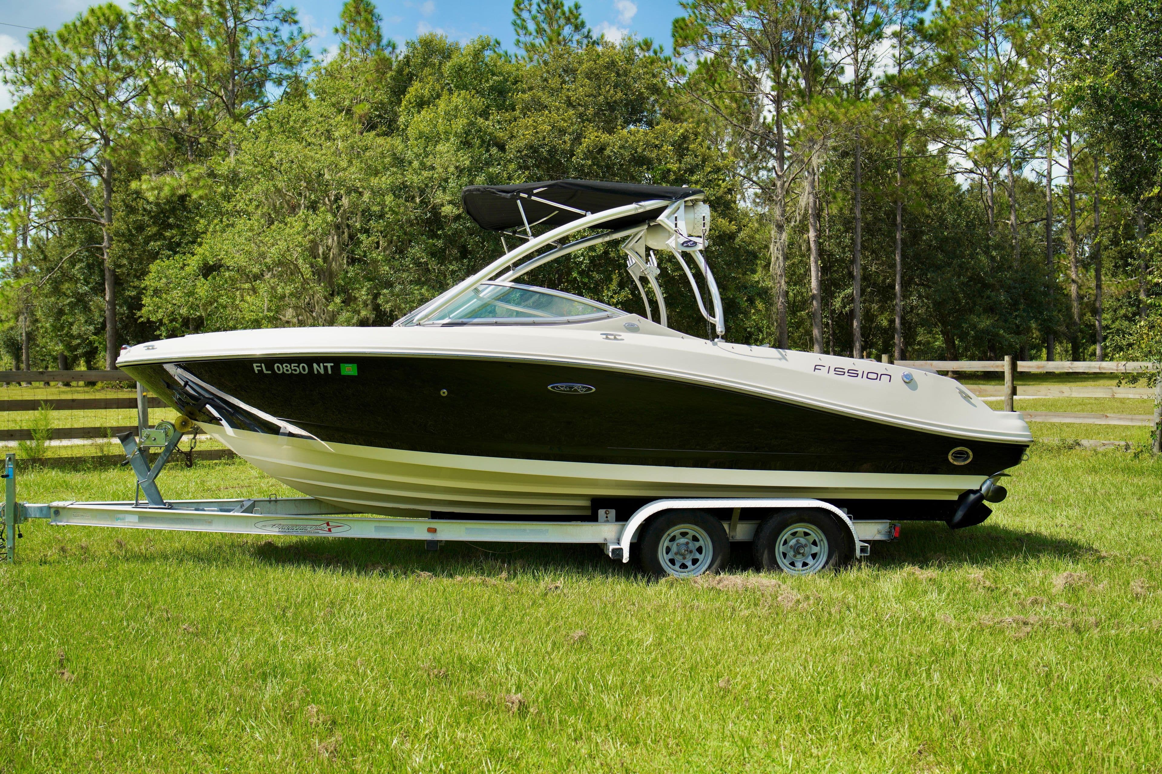 2008 Sea Ray 230 Select Fission boat on a trailer in a grassy area.