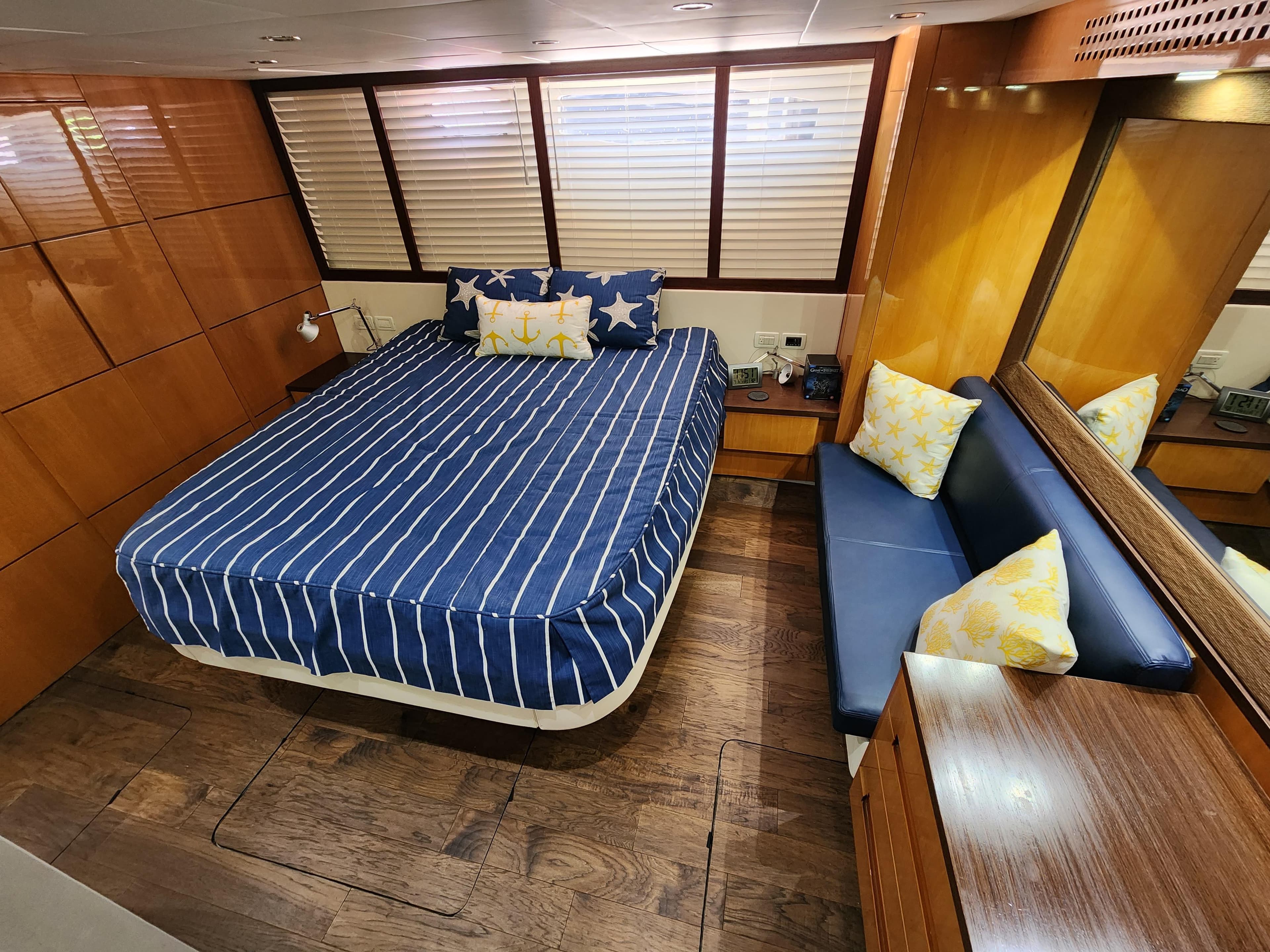 Luxurious bedroom in a 2006 Pershing Cruiser with wooden accents and striped bedding.
