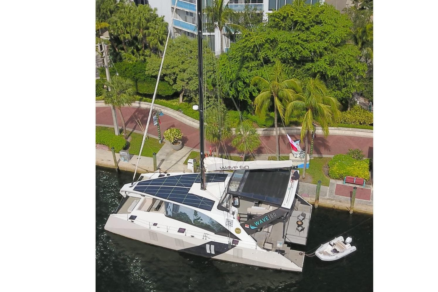 Aerial view of 2024 Wave Wave60 yacht docked, featuring solar panels and lush surroundings.