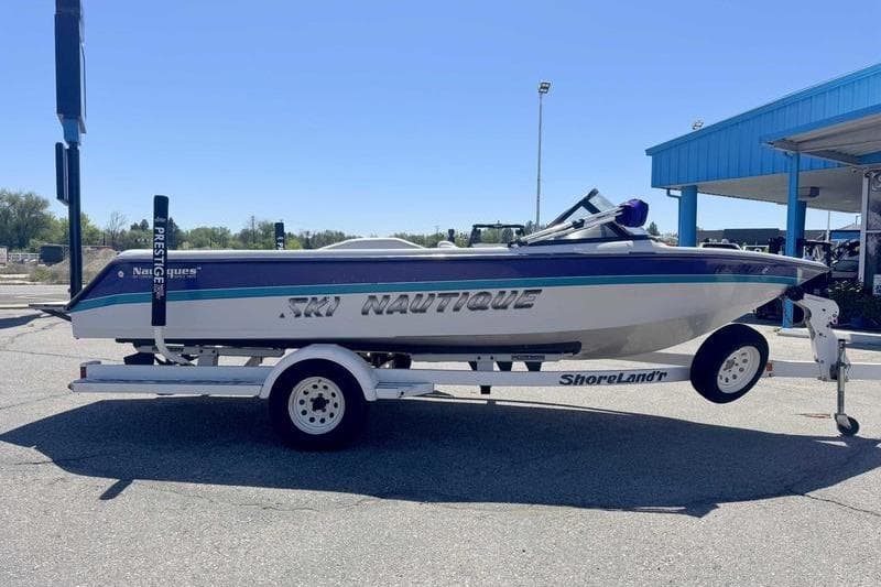 1995 Correct Craft Ski Nautique boat on trailer, parked outdoors under clear blue sky.