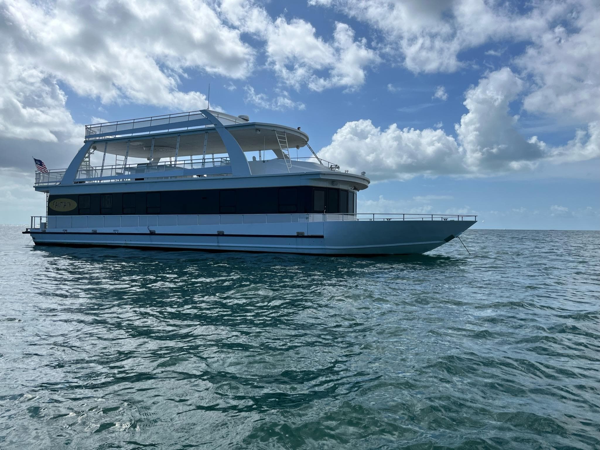 2009 Fantasy Houseboat on open water under a partly cloudy sky.