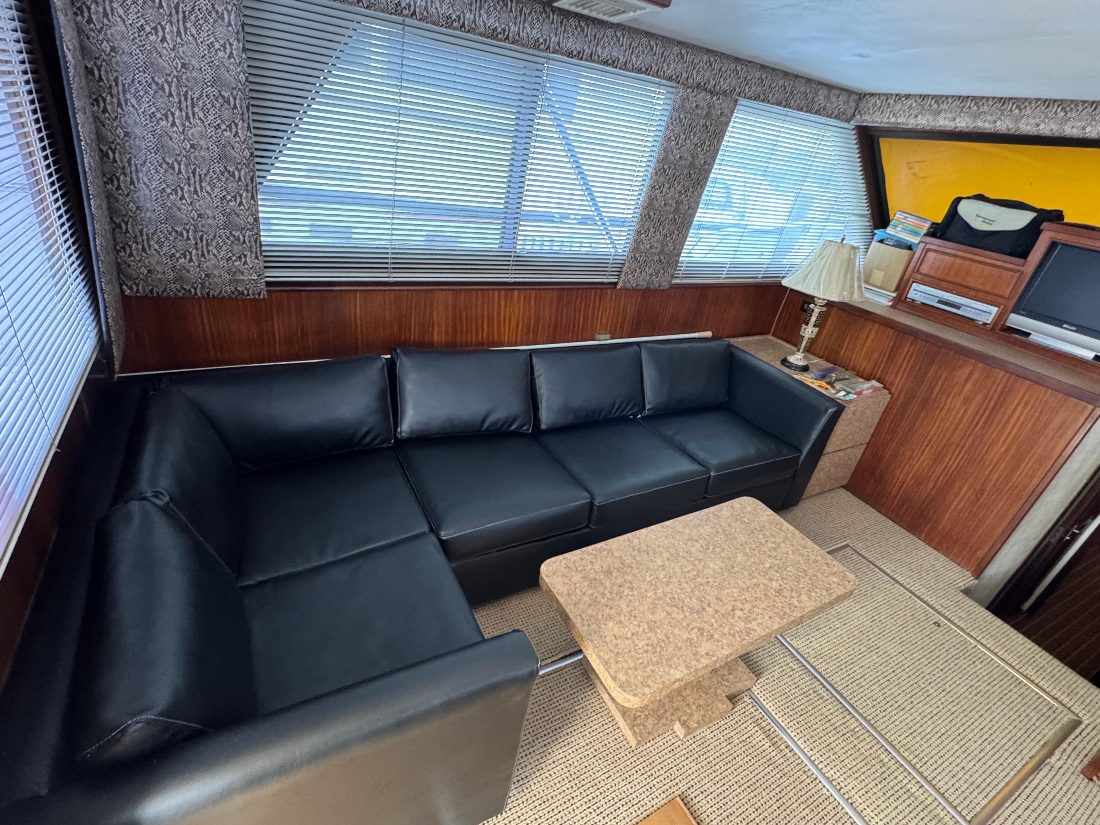 Interior of 1984 Hatteras 46 Convertible yacht with black leather sofa and wooden accents.