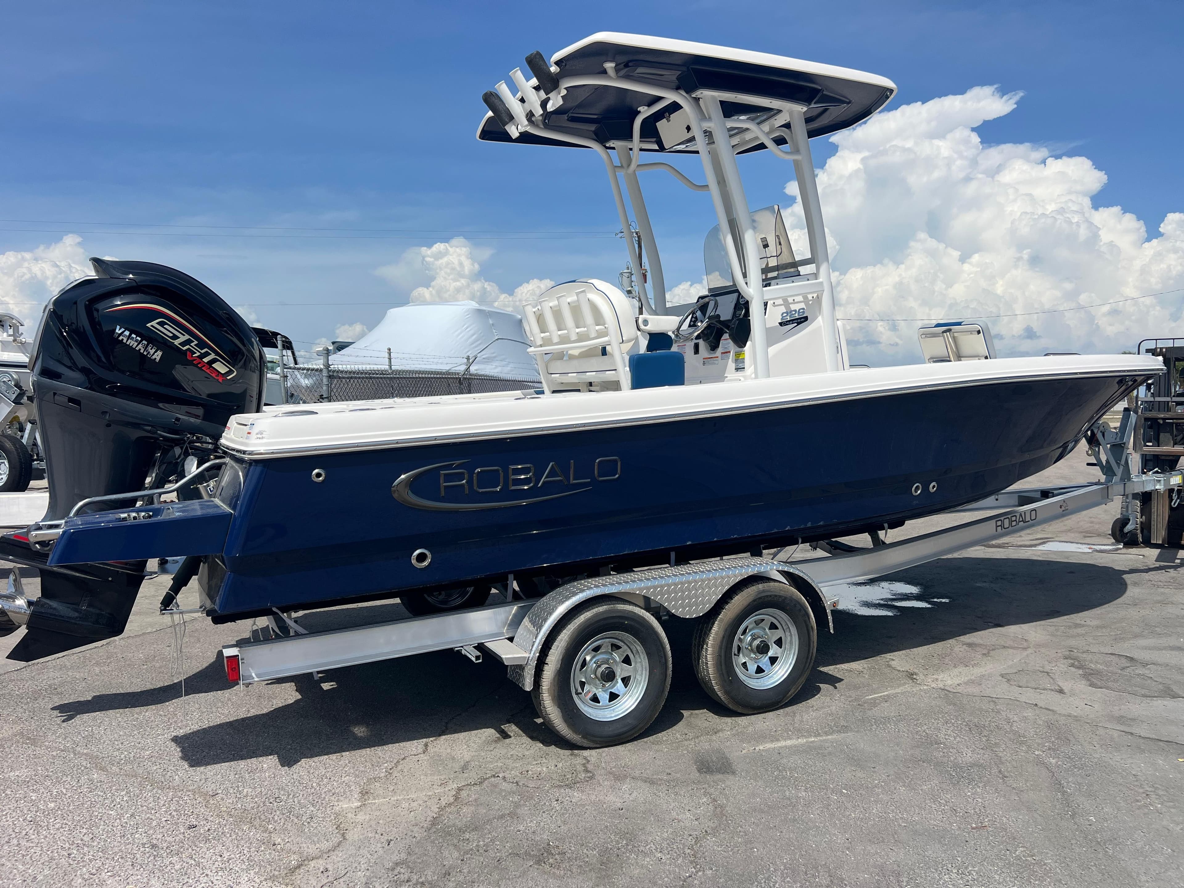 2025 Robalo 226 Cayman boat on trailer, blue hull, Yamaha engine, sunny day.