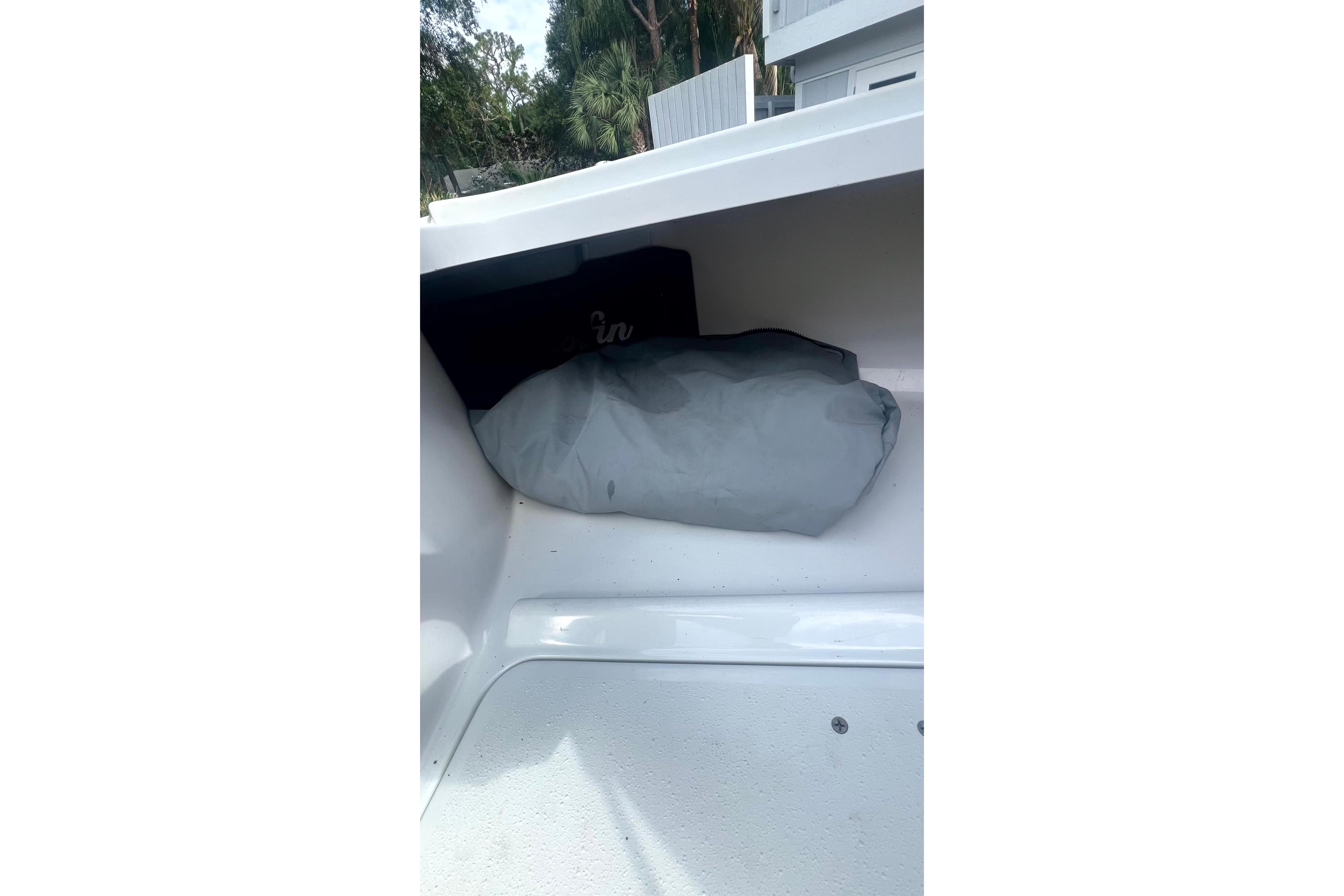 Storage compartment in a 2017 Yellowfin 21 Hybrid boat with a gray cover inside.