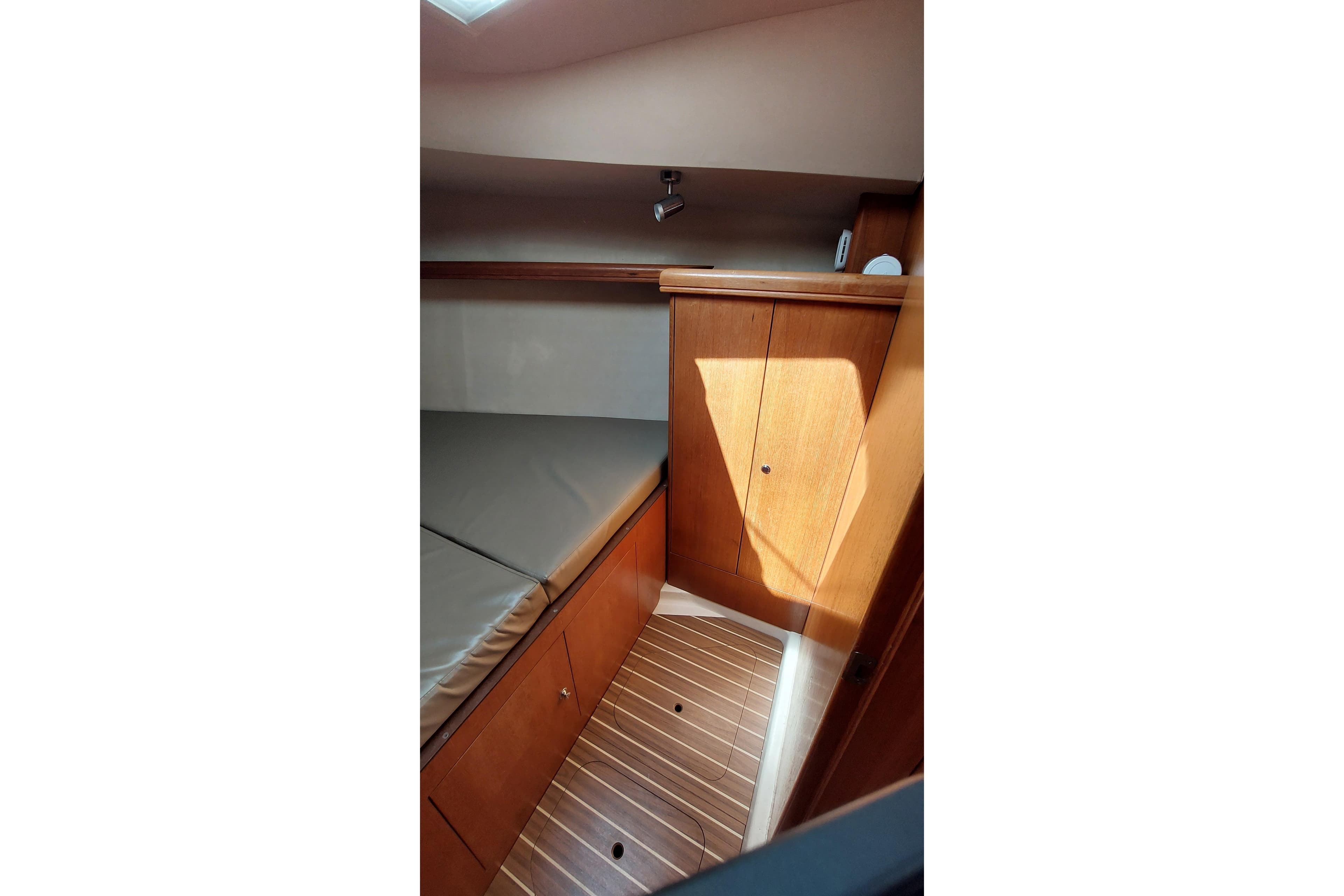 Interior cabin of 2005 Hunter 38 sailboat with wooden cabinetry and cushioned seating.