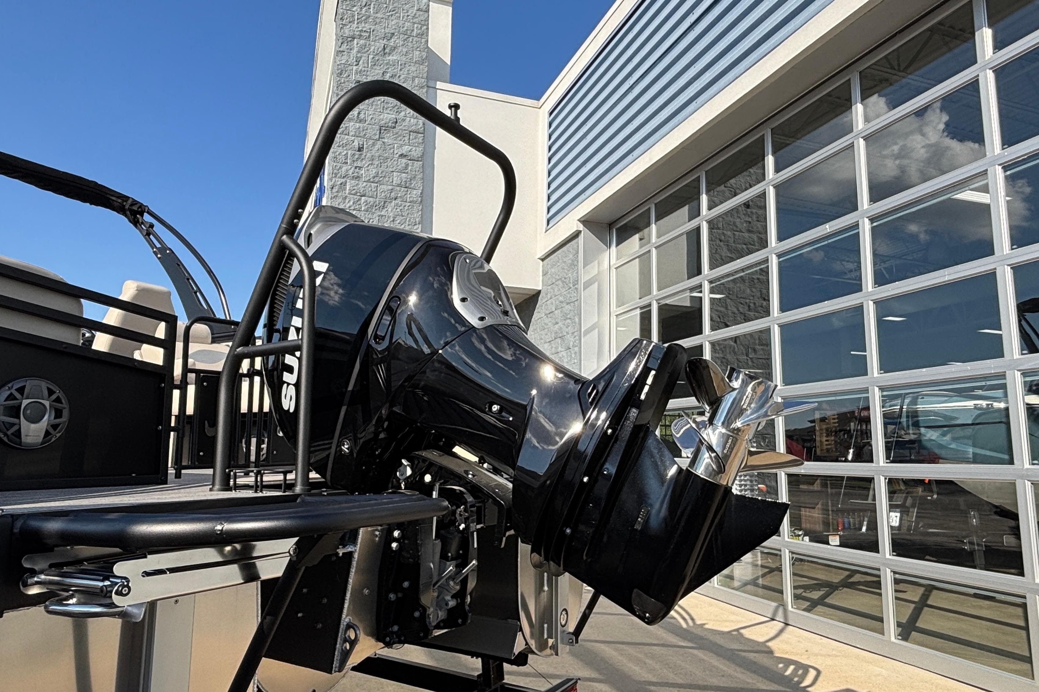 2026 JC Neptoon 25TT Sport boat with powerful outboard motor, parked near modern building.
