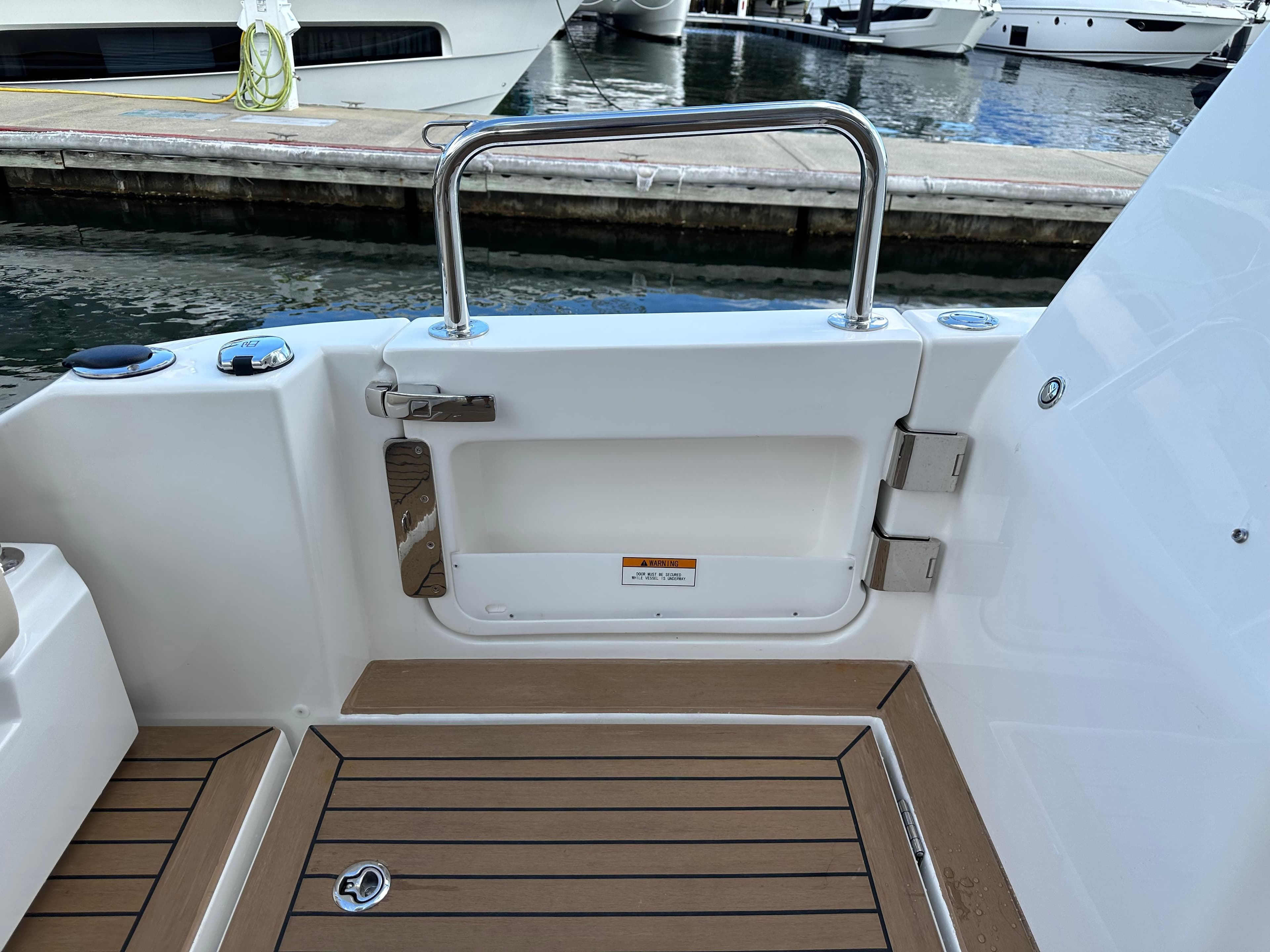 Aquila 36 Sport 2025 boat deck with teak flooring and stainless steel railing.