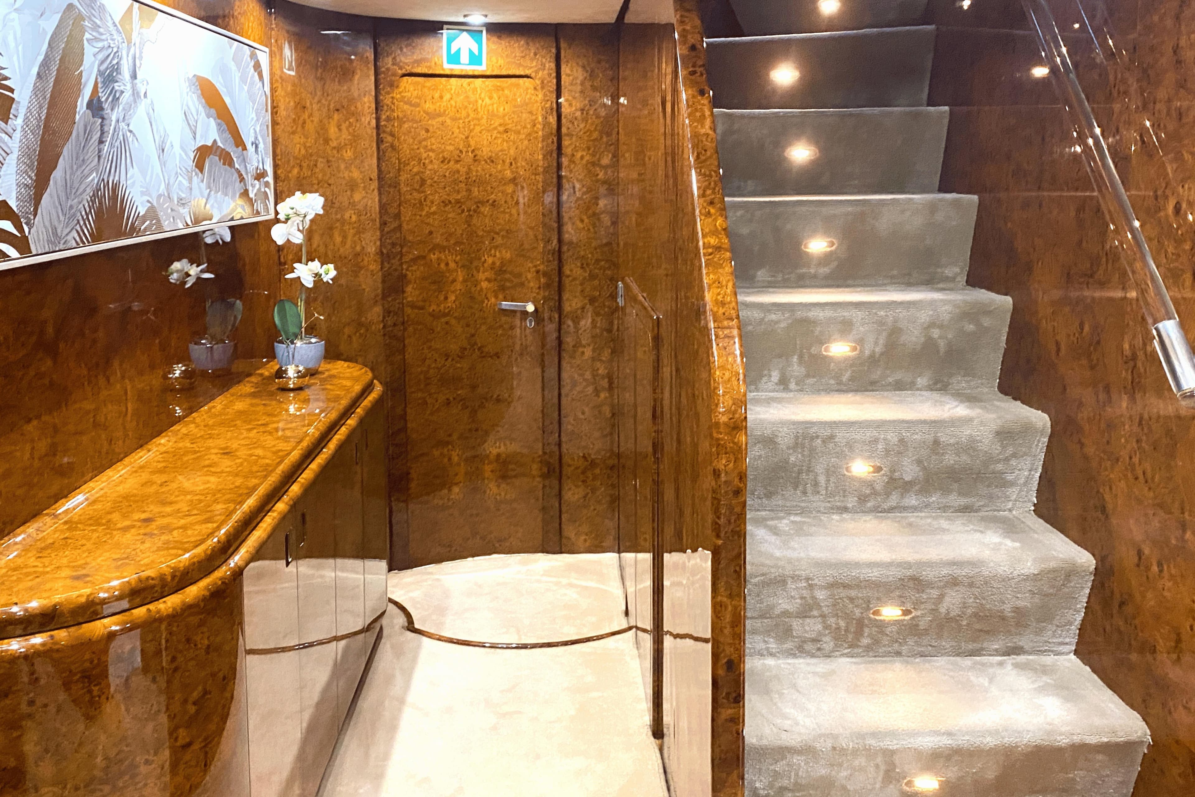 Luxurious Mondomarine 120 yacht interior with elegant wood paneling and illuminated staircase, 1995 model.