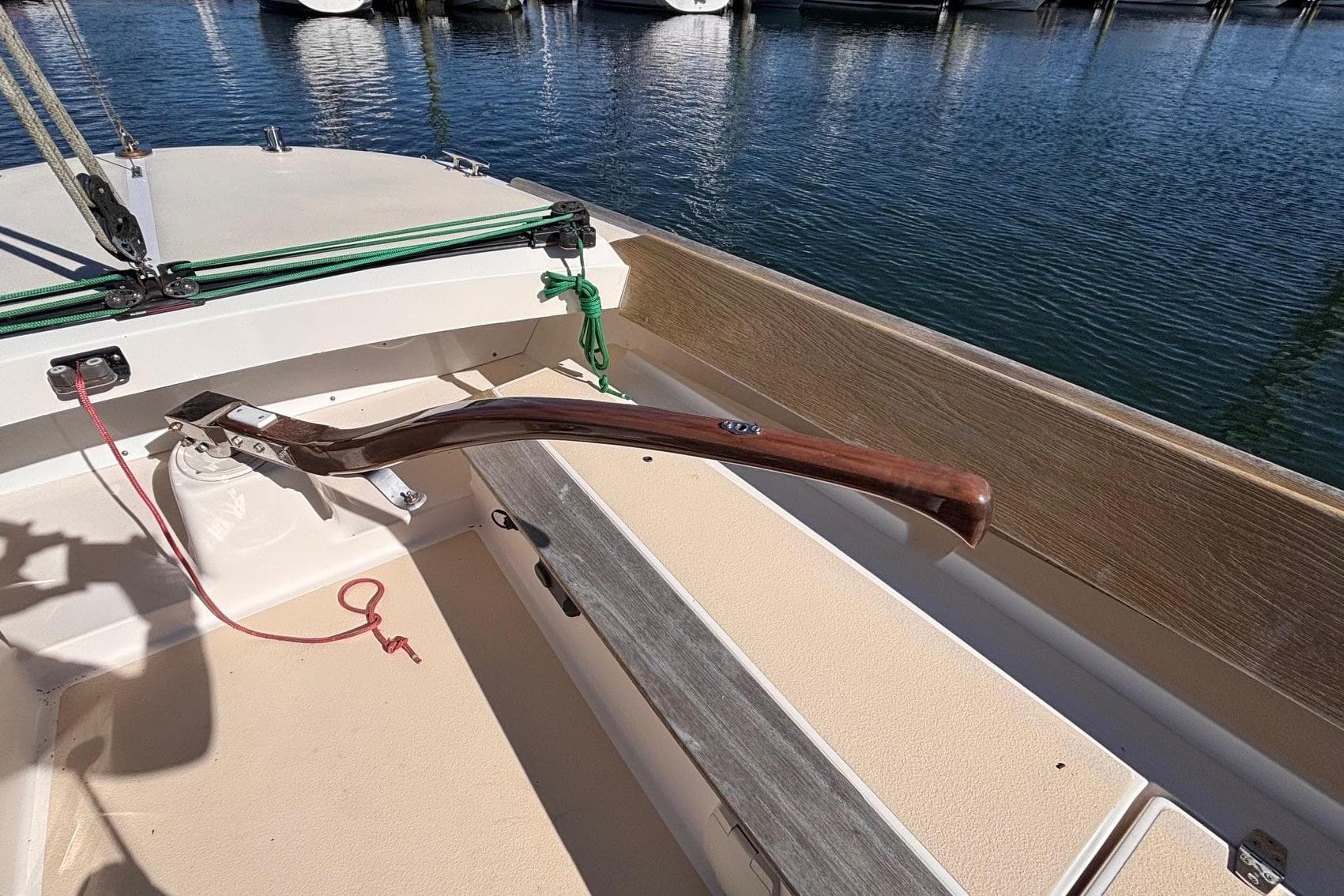 2016 Alerion Express 28 sailboat cockpit with wooden tiller and marina view.