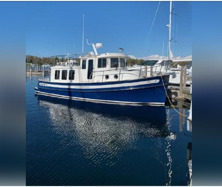 2010 Nordic Tug 32 boat docked in a marina on a sunny day.