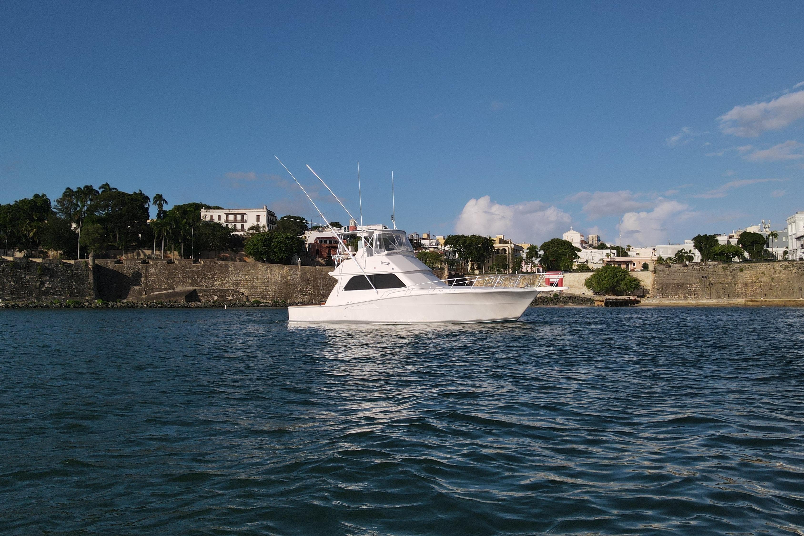 1999 Viking 43 Convertible yacht on calm water near historic coastal town.
