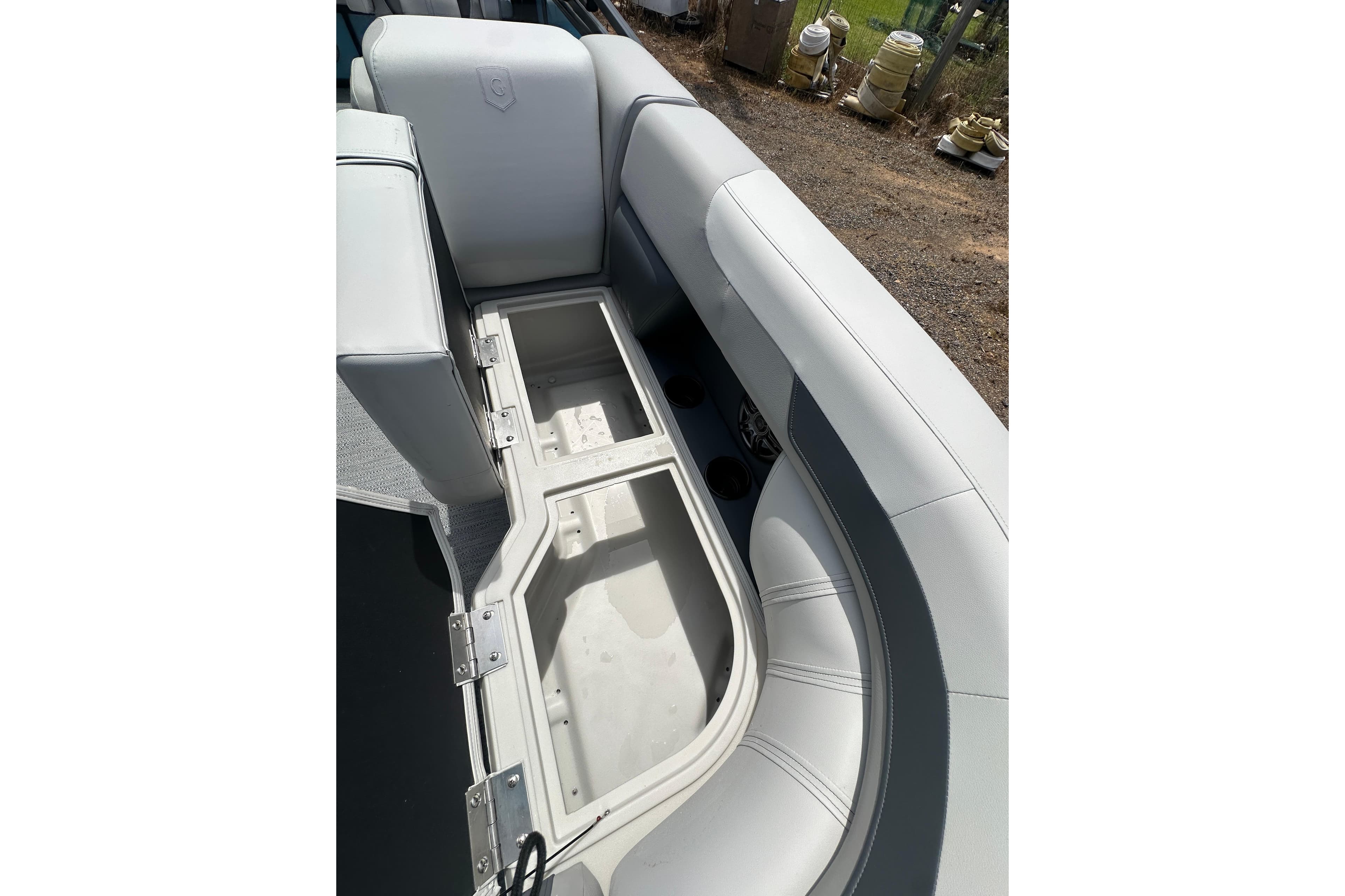 Open storage compartment in 2026 Godfrey Sweetwater 2286 SFLC boat with cushioned seating.