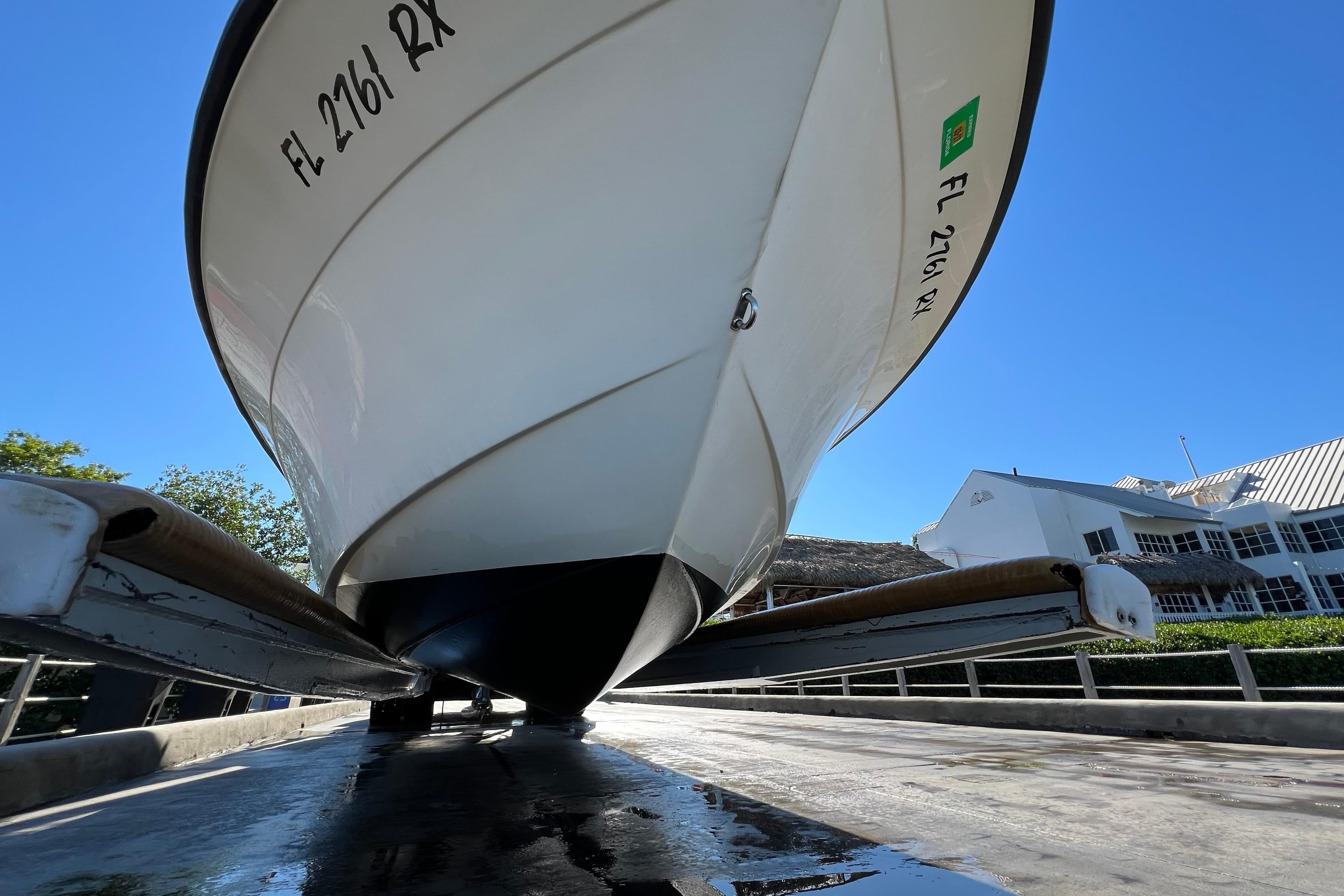 2004 Hydra-Sports 212 CC boat on trailer, viewed from below, against clear blue sky.