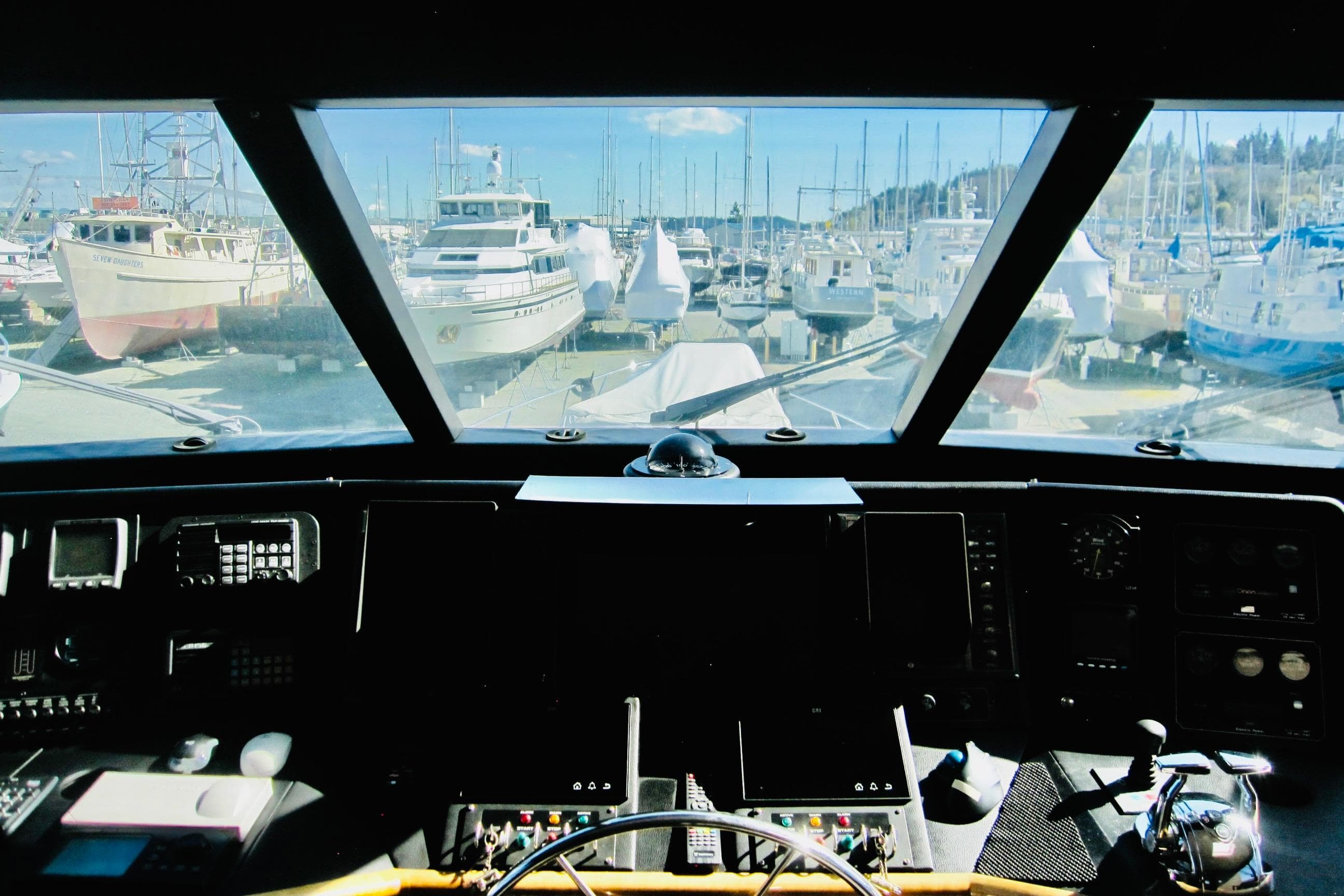 Pilothouse view from 1999 Delta Marine Raised Pilothouse Motoryacht, overlooking marina with docked boats.