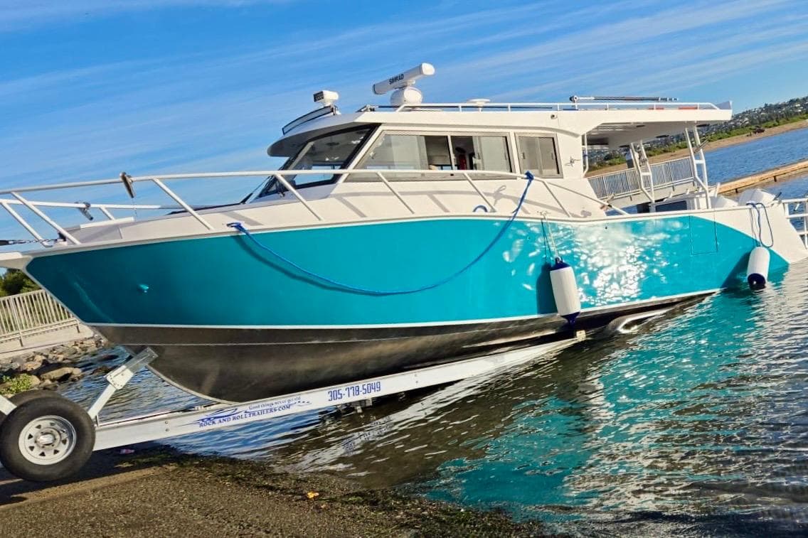 Custom Boat 34, 2025 model, turquoise hull, docked on a trailer by the water.