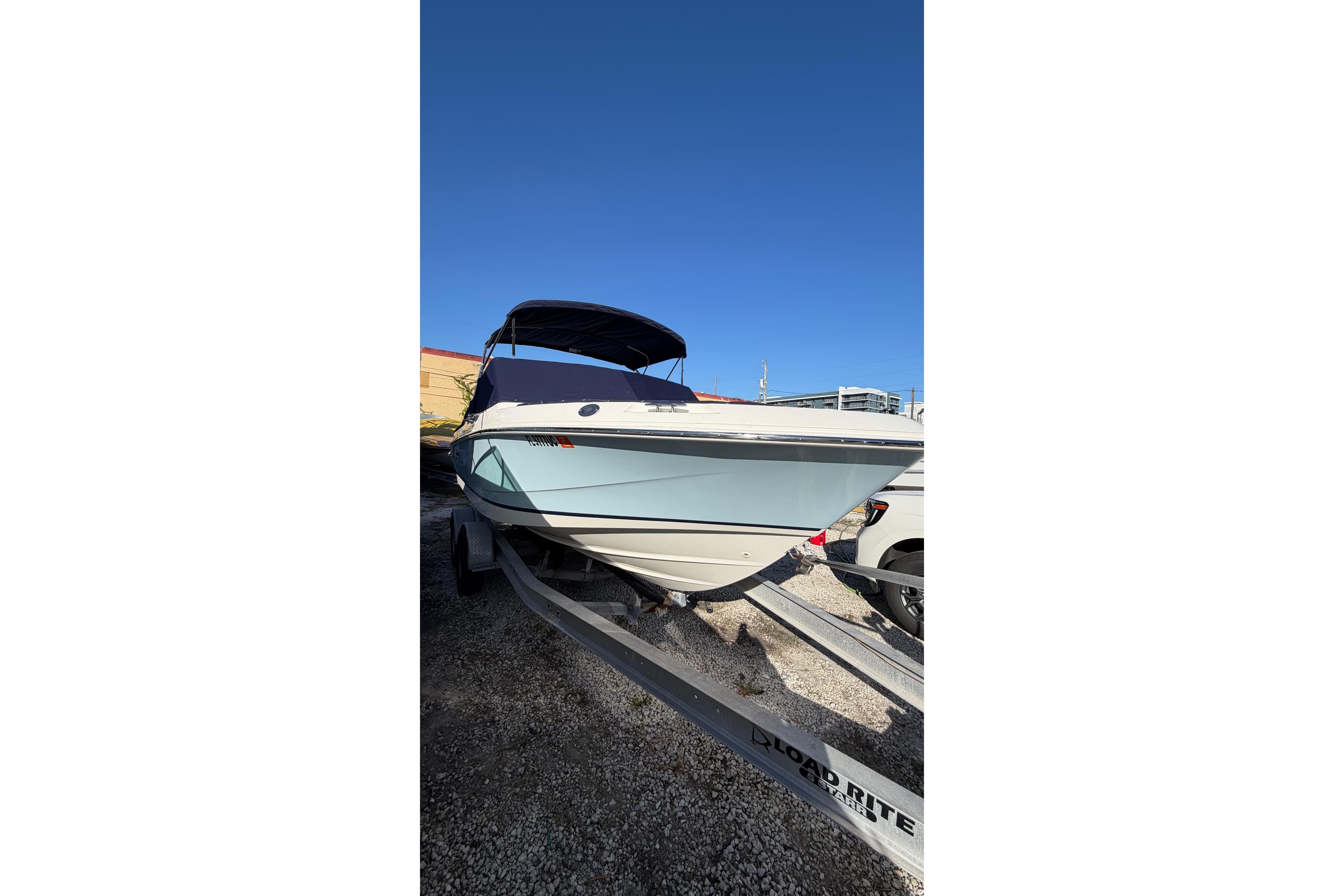 2024 Boston Whaler 210 Vantage boat on trailer under clear blue sky.