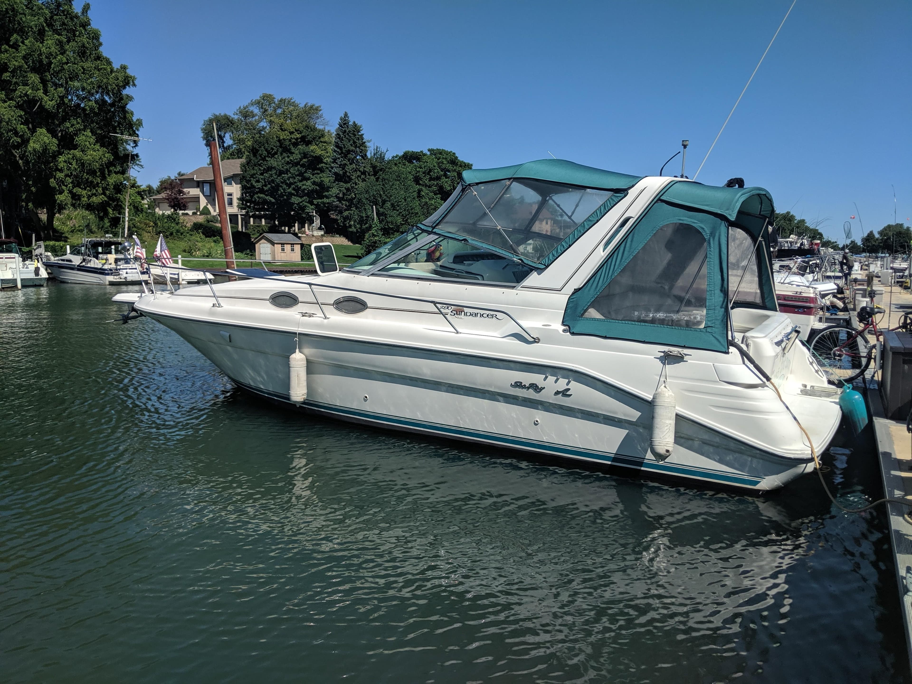 1996 Sea Ray 290 Sundancer boat docked in a marina with a green canopy.
