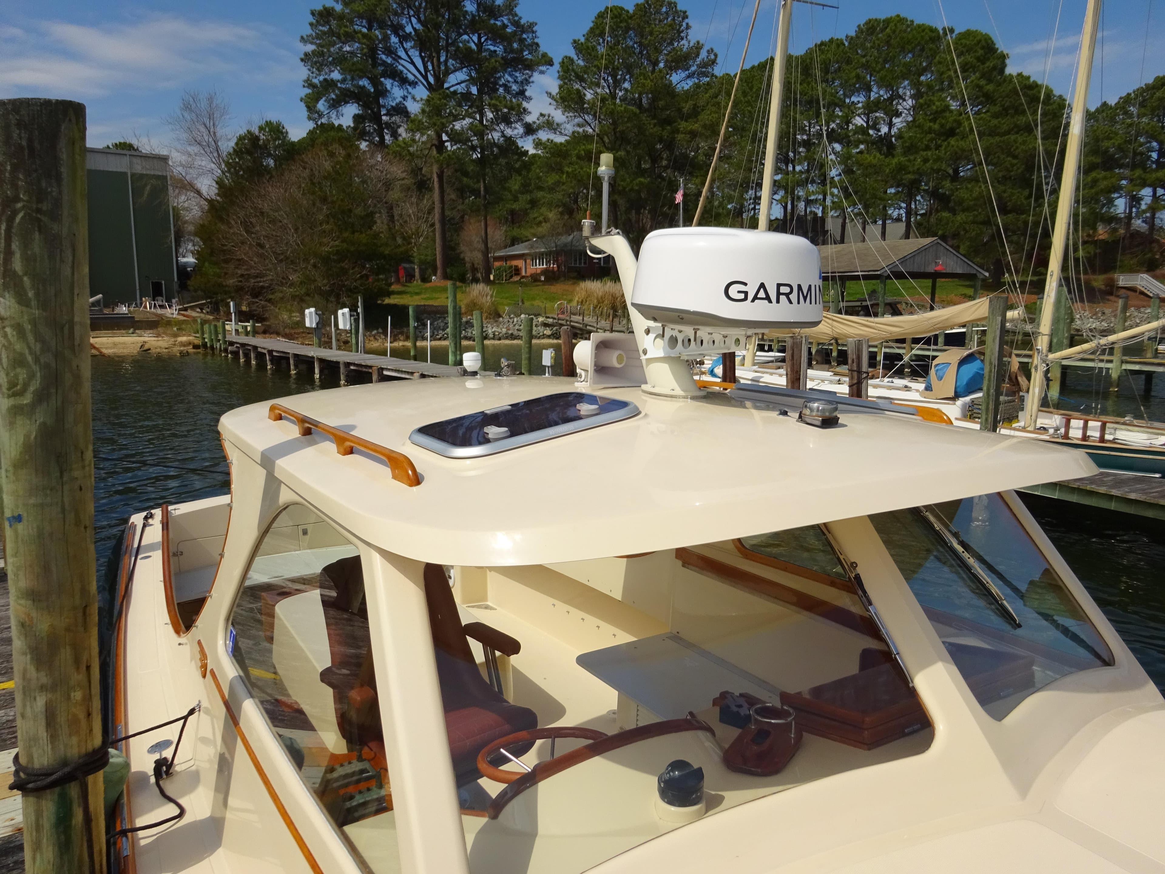 1995 Hinckley Picnic Boat Classic docked, featuring Garmin equipment, surrounded by trees and water.
