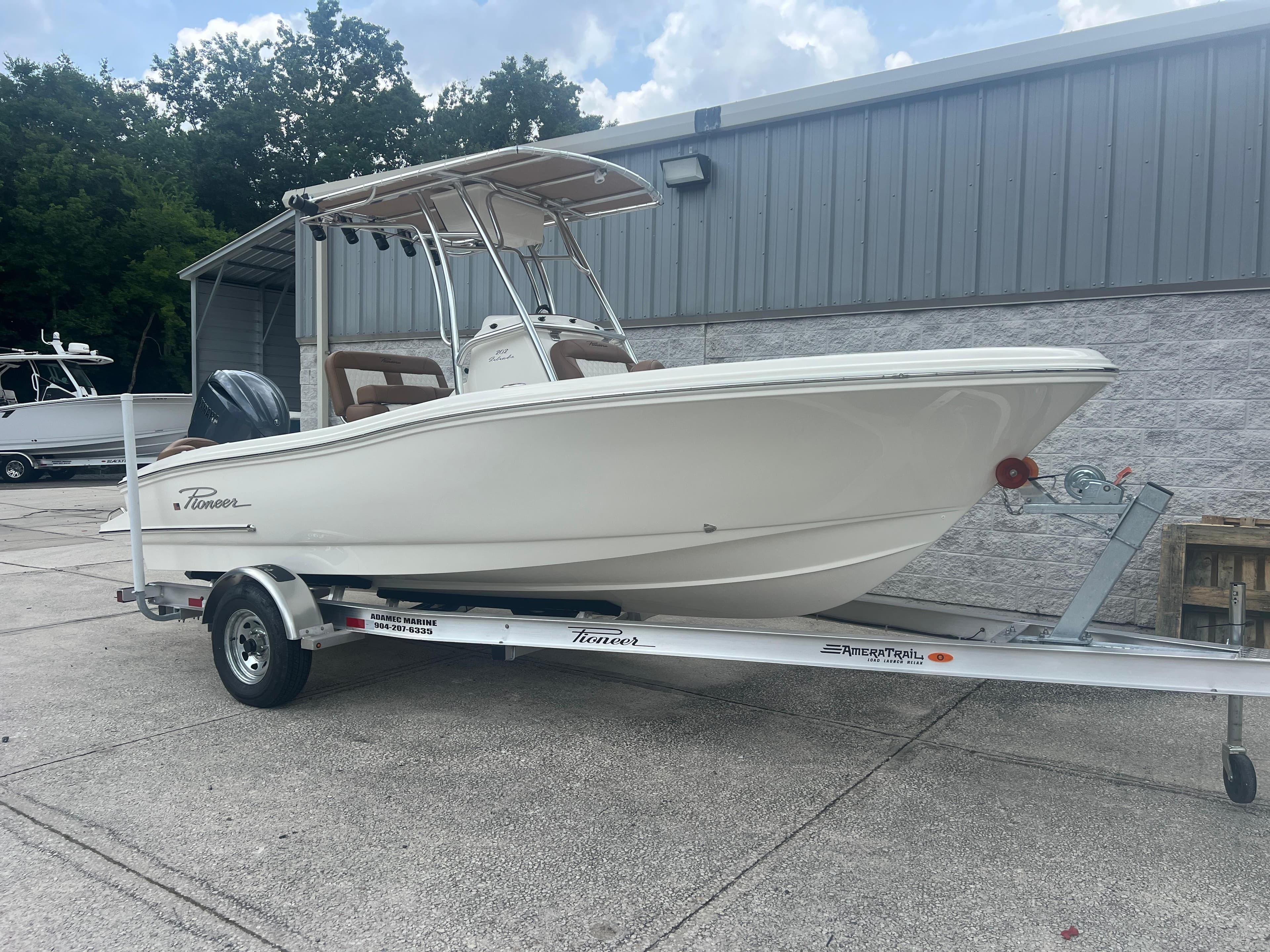 2026 Pioneer 202 Islander boat on trailer, parked outdoors near a metal building.
