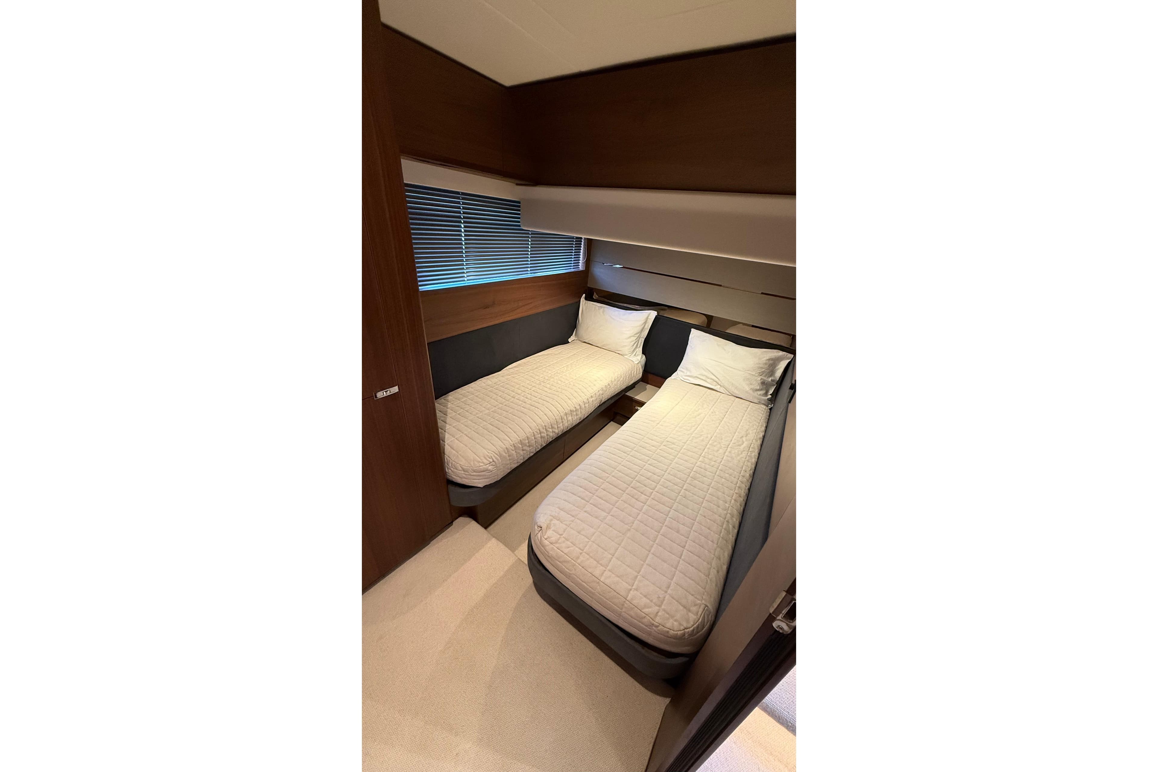 Twin beds in a 2021 Princess S62 yacht cabin with modern wood paneling.
