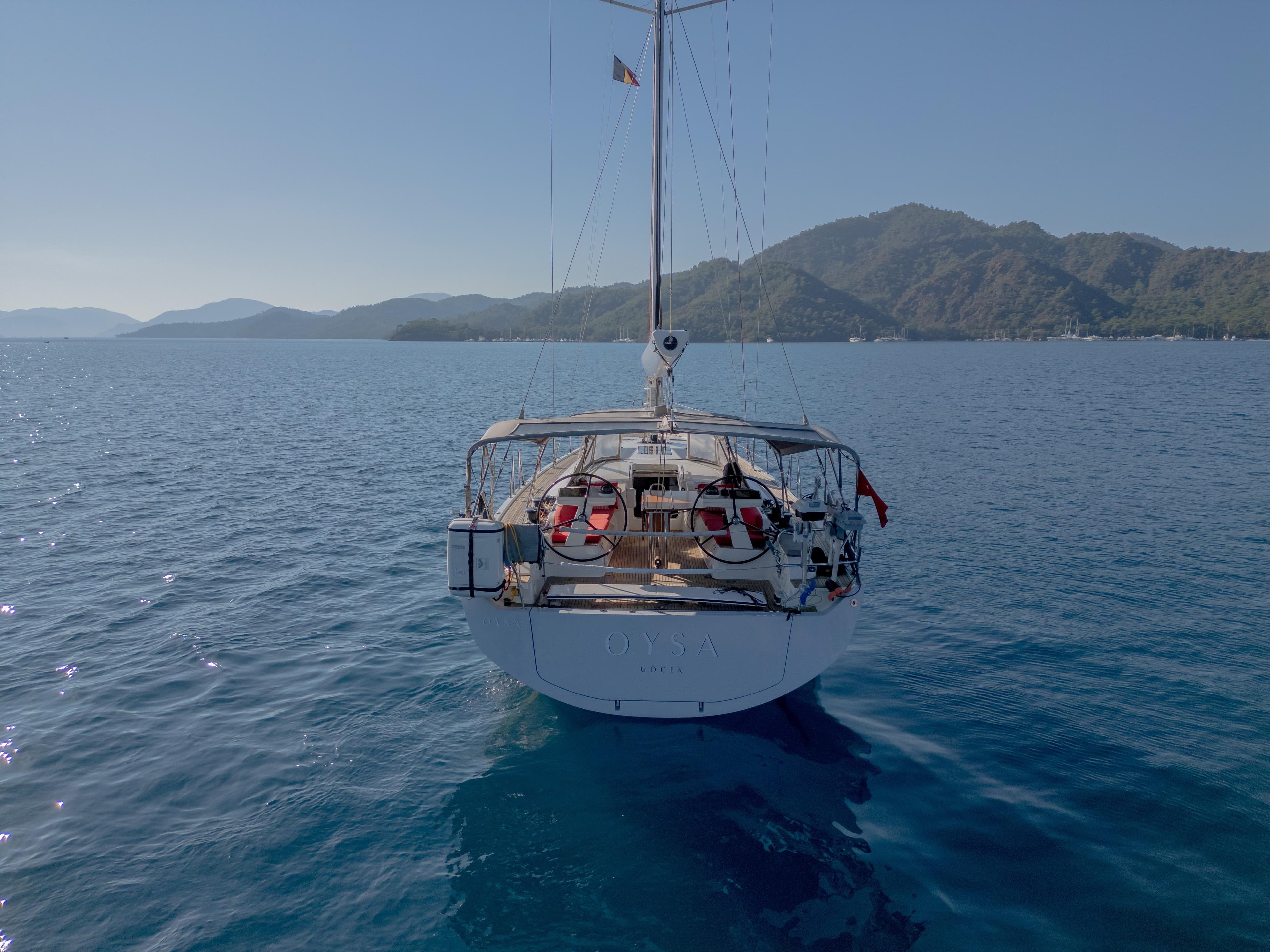 Nautor Swan 48 yacht sailing on calm blue waters, mountainous backdrop, 2020 model.