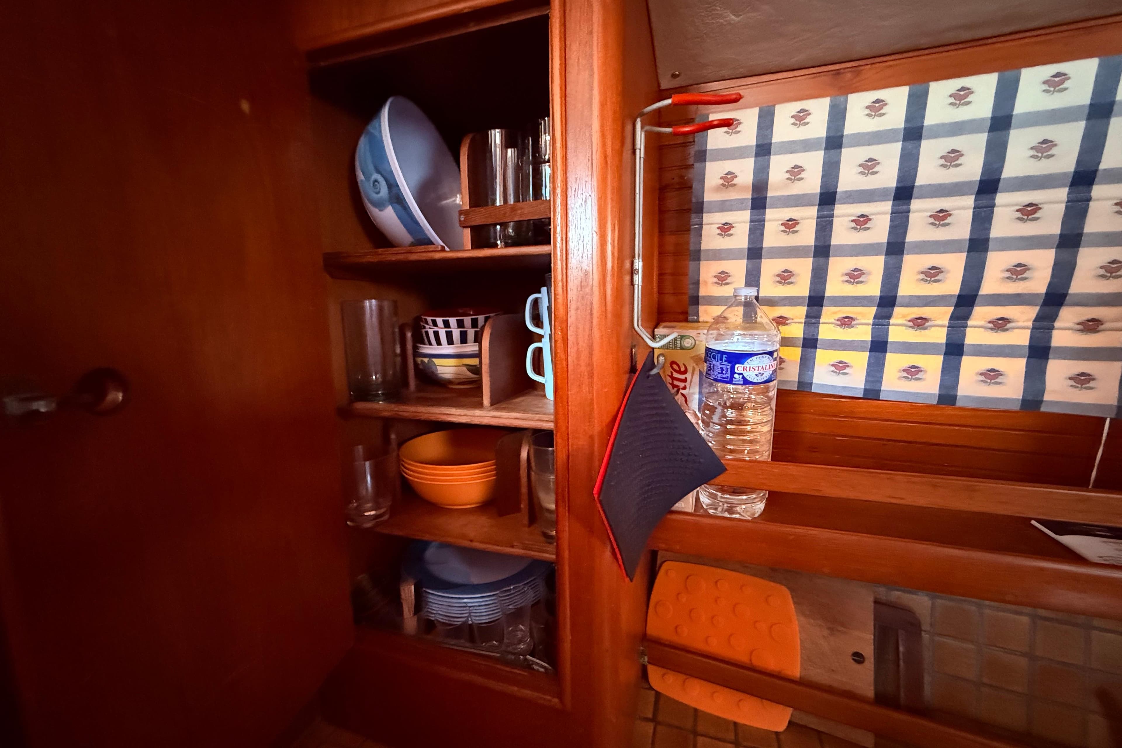 Wooden cabinet with dishes and glasses inside a 1983 Moody 134 Grenadier boat.