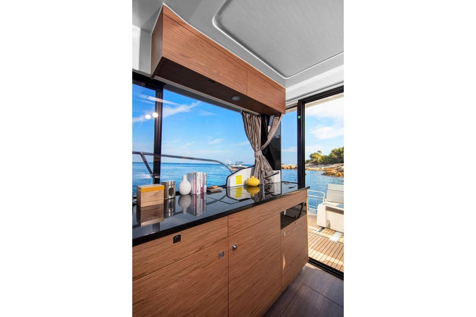 Modern kitchen interior of 2026 Jeanneau NC 1095 Coupe yacht with ocean view.