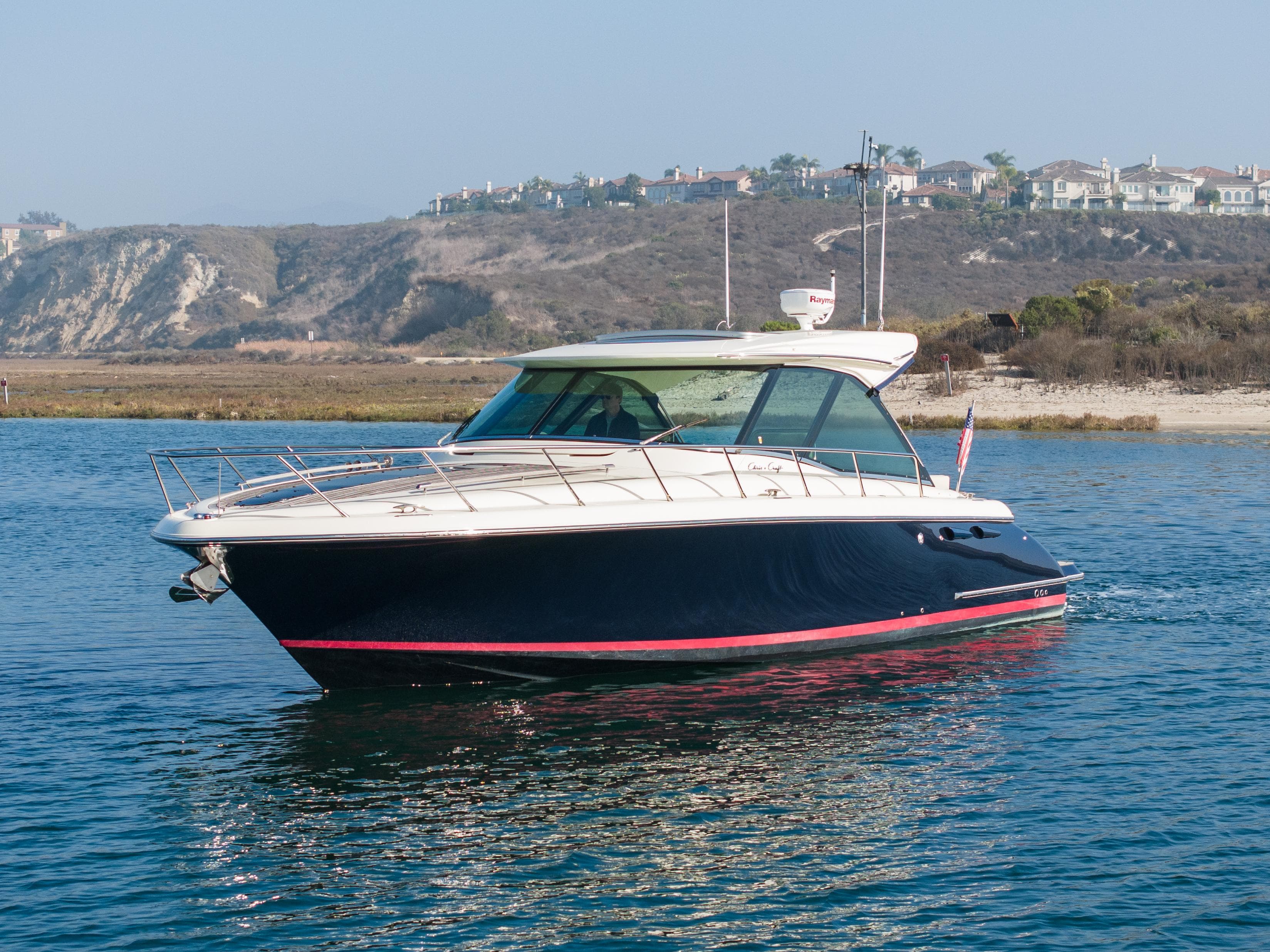 2014 Chris-Craft Corsair 36 Hard Top boat on calm water near coastal cliffs.