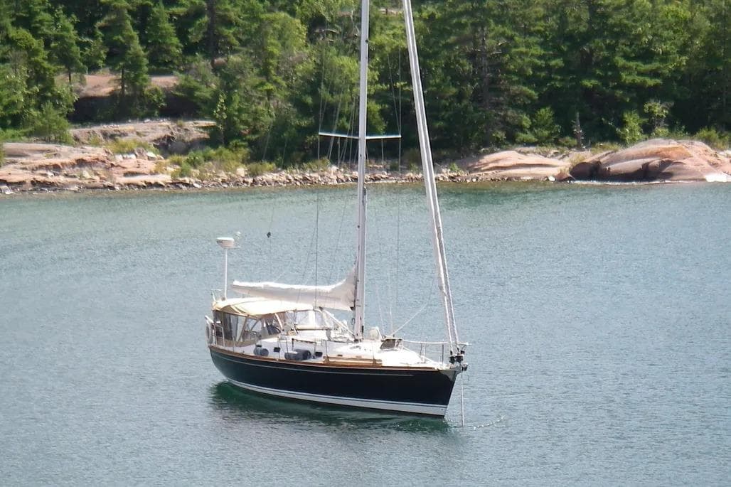 Sailboat Tartan 4300 (2009) anchored in a serene lake with forested shoreline.