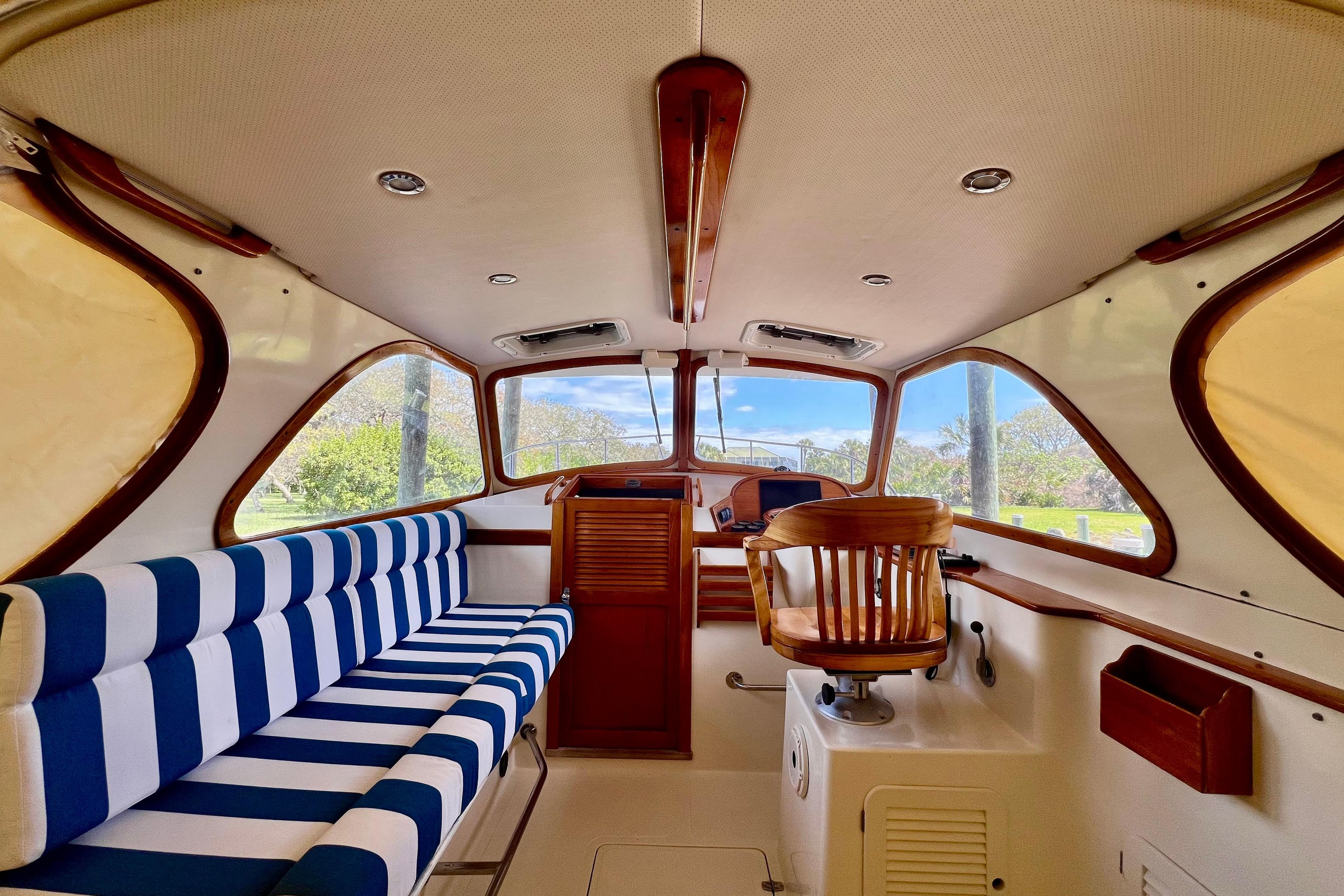 Interior of a 1995 Hinckley Picnic Boat 36 Classic with striped seating and wooden helm.