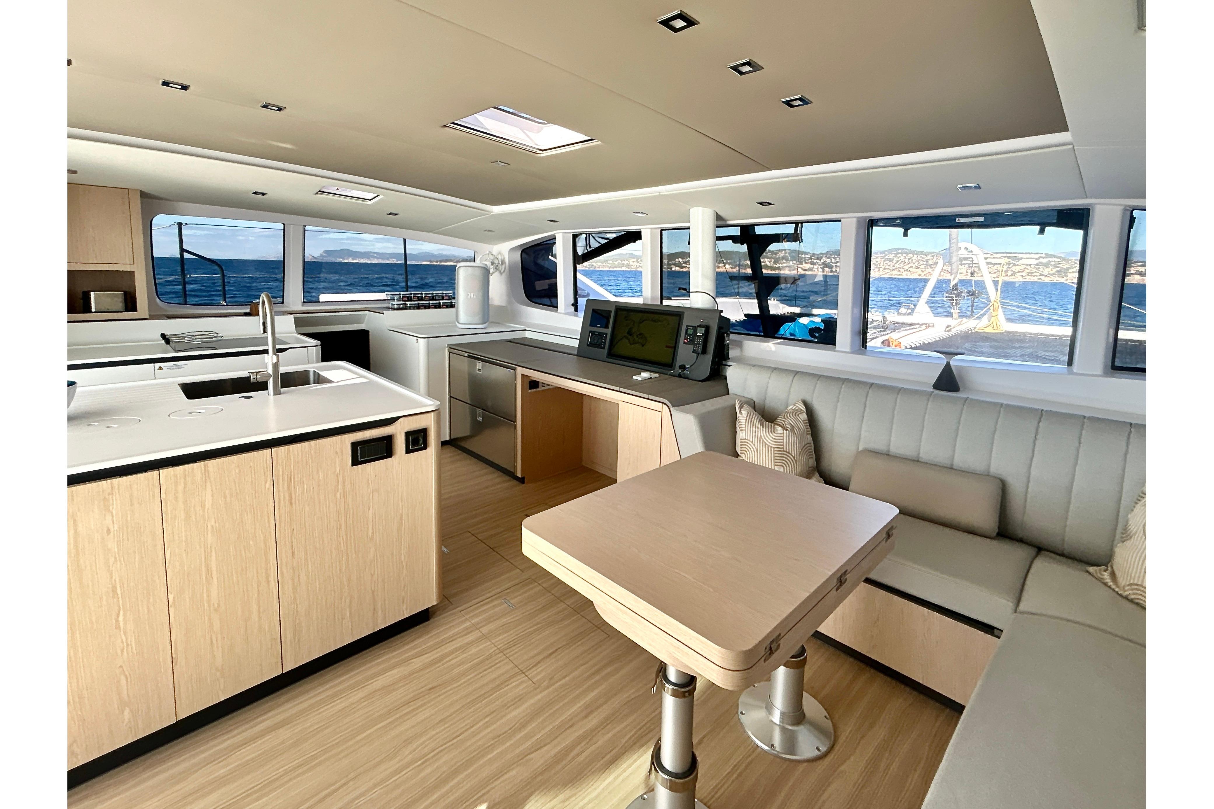 Luxurious interior of 2025 Outremer 55 catamaran with modern kitchen and seating area.