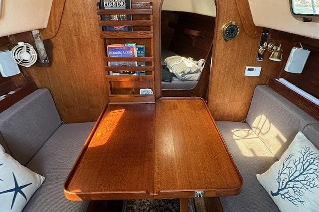 Cozy 1987 J Boats J28 cabin interior with wooden table and nautical decor.