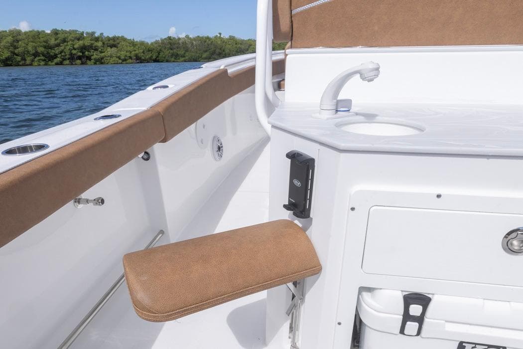 2026 Sea Hunt Ultra 275 SE boat interior with seating and sink, on calm water.