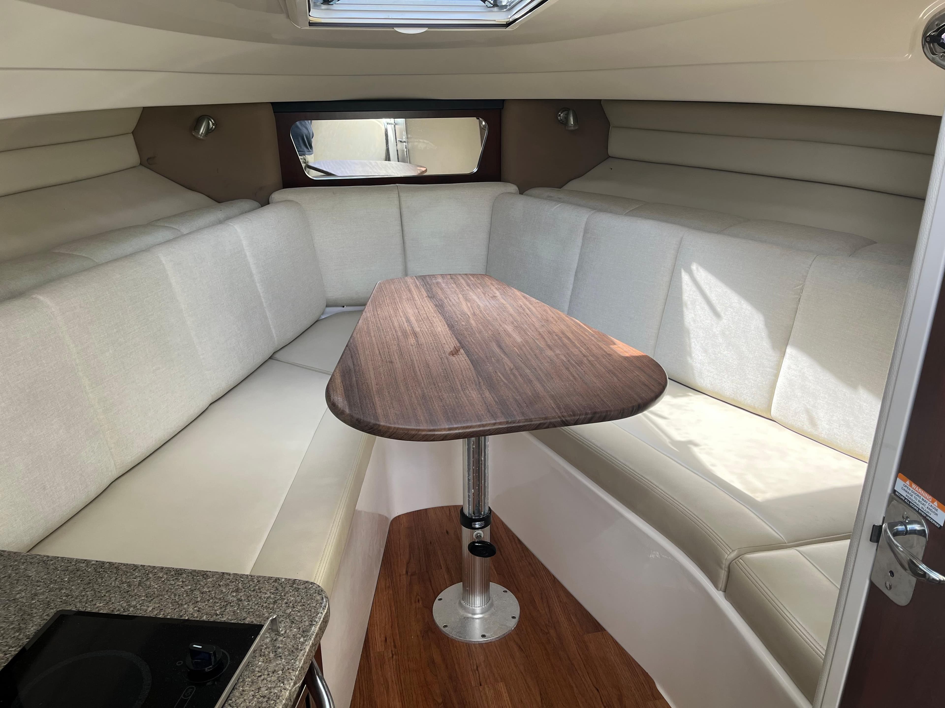 Interior of 2015 Robalo R305 Walkaround with cushioned seating and wooden table.