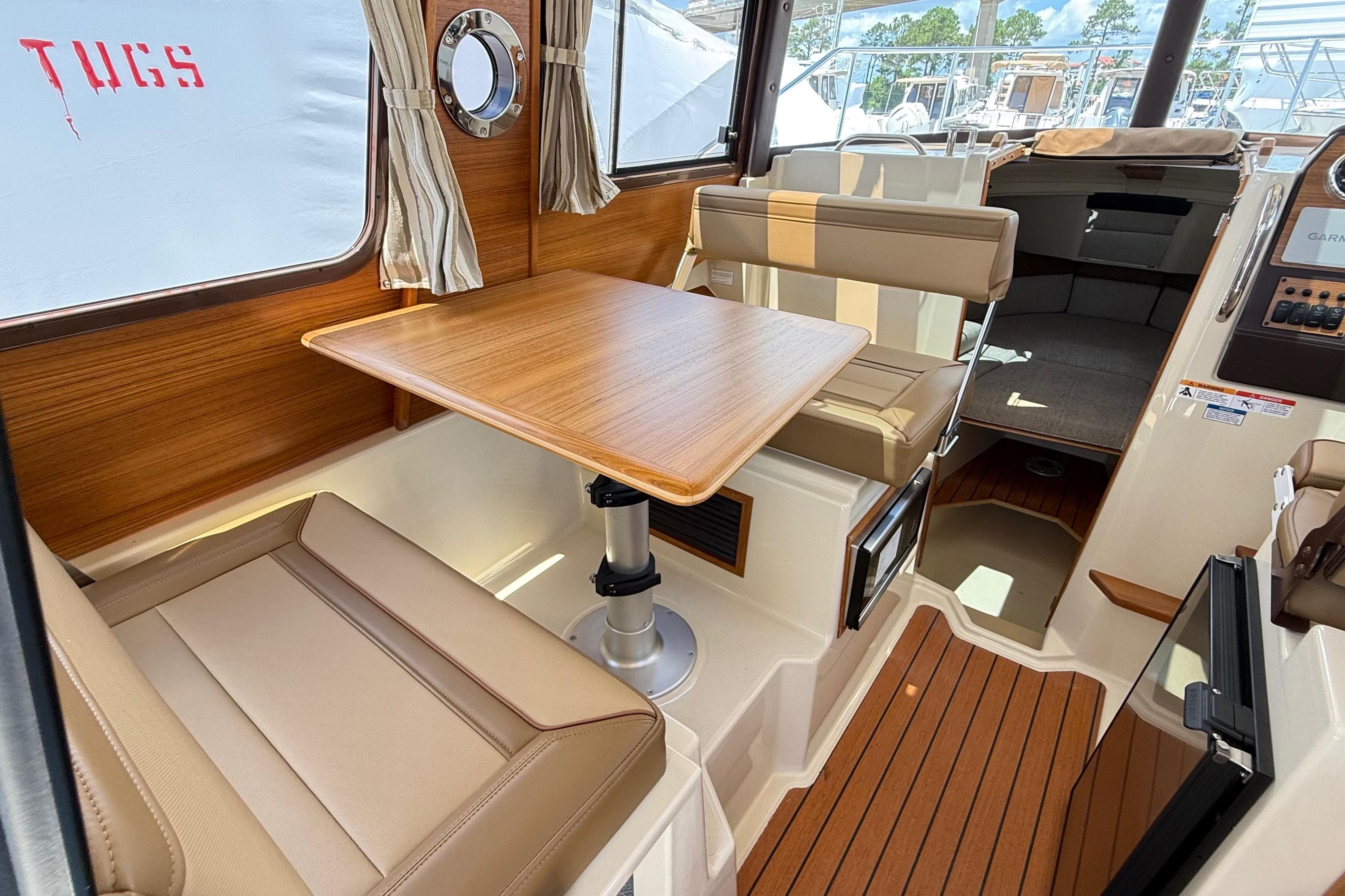 2025 Ranger Tugs R-23 interior with wood table, beige seating, and nautical decor.
