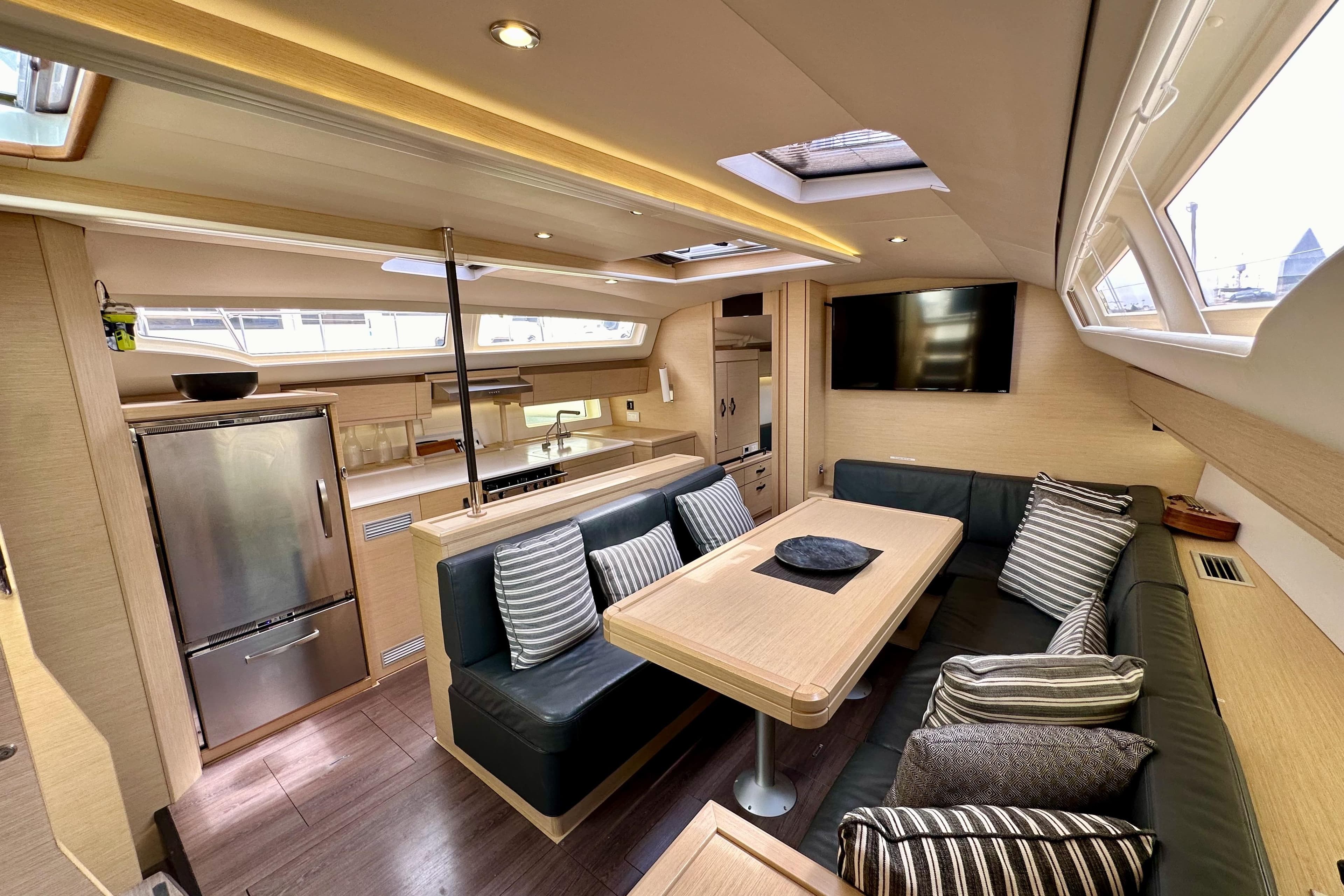 Luxurious interior of a 2018 Jeanneau 54 yacht with modern kitchen and cozy seating area.