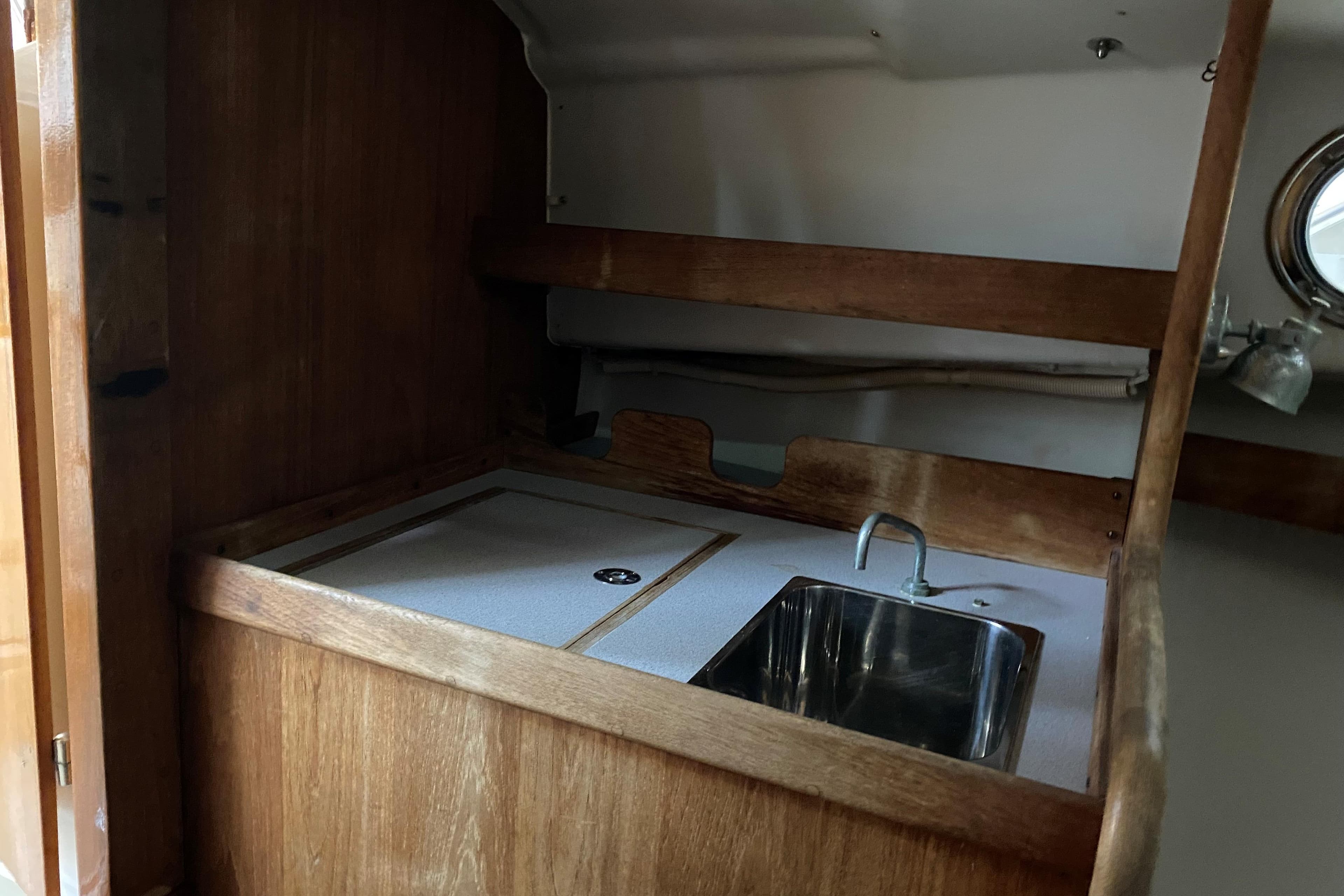 1997 Wasque C.W.Hood Wasque 26 boat interior with wooden cabinetry and stainless steel sink.