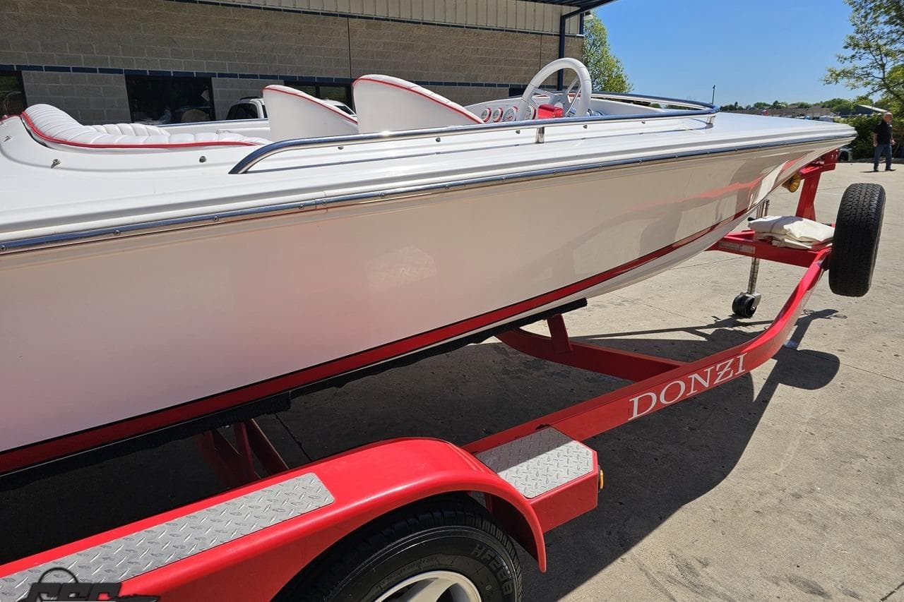 1997 Donzi 18 Classic boat on a red trailer, parked outdoors.