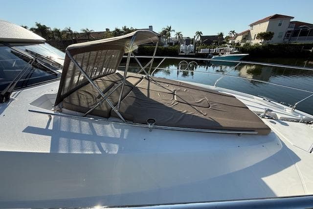 2015 Prestige 500 yacht with sunshade, docked in a serene waterfront setting.