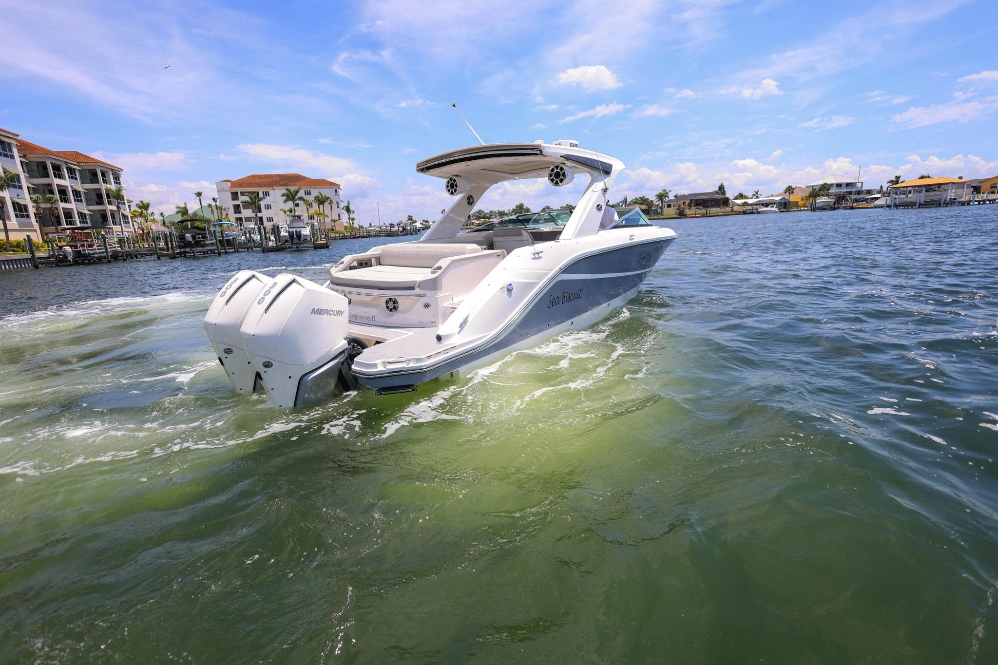 2022 Sea Ray SLX 310 Outboard cruising on a sunny day near waterfront buildings.